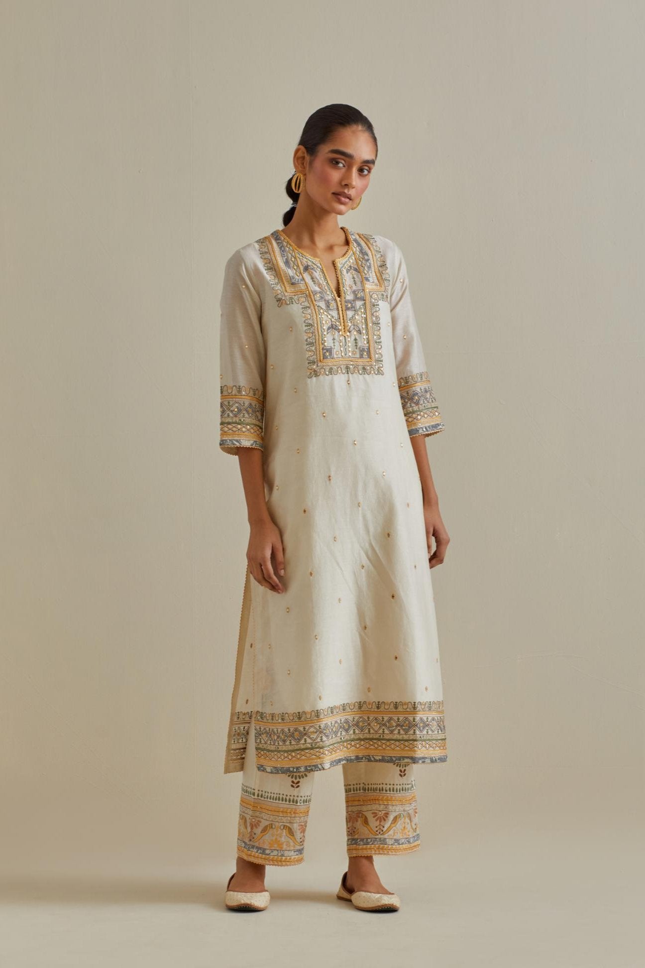 Yellow and off-white cotton chanderi straight kurta set with yoke with patchwork and silk thread embroidery highlighted with mirror, sequins, tassels and braids.