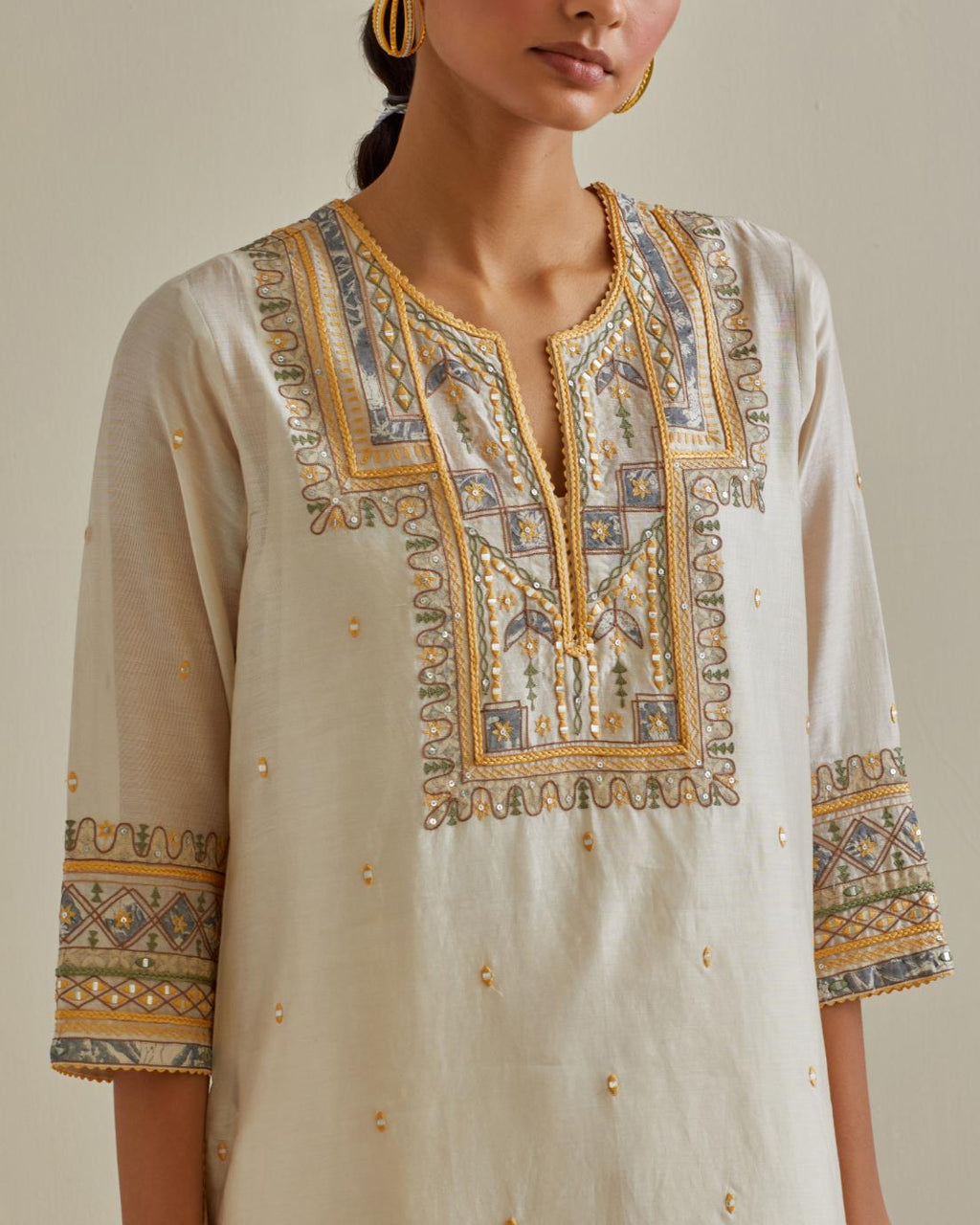 Yellow and off-white cotton chanderi straight kurta set with yoke with patchwork and silk thread embroidery highlighted with mirror, sequins, tassels and braids.