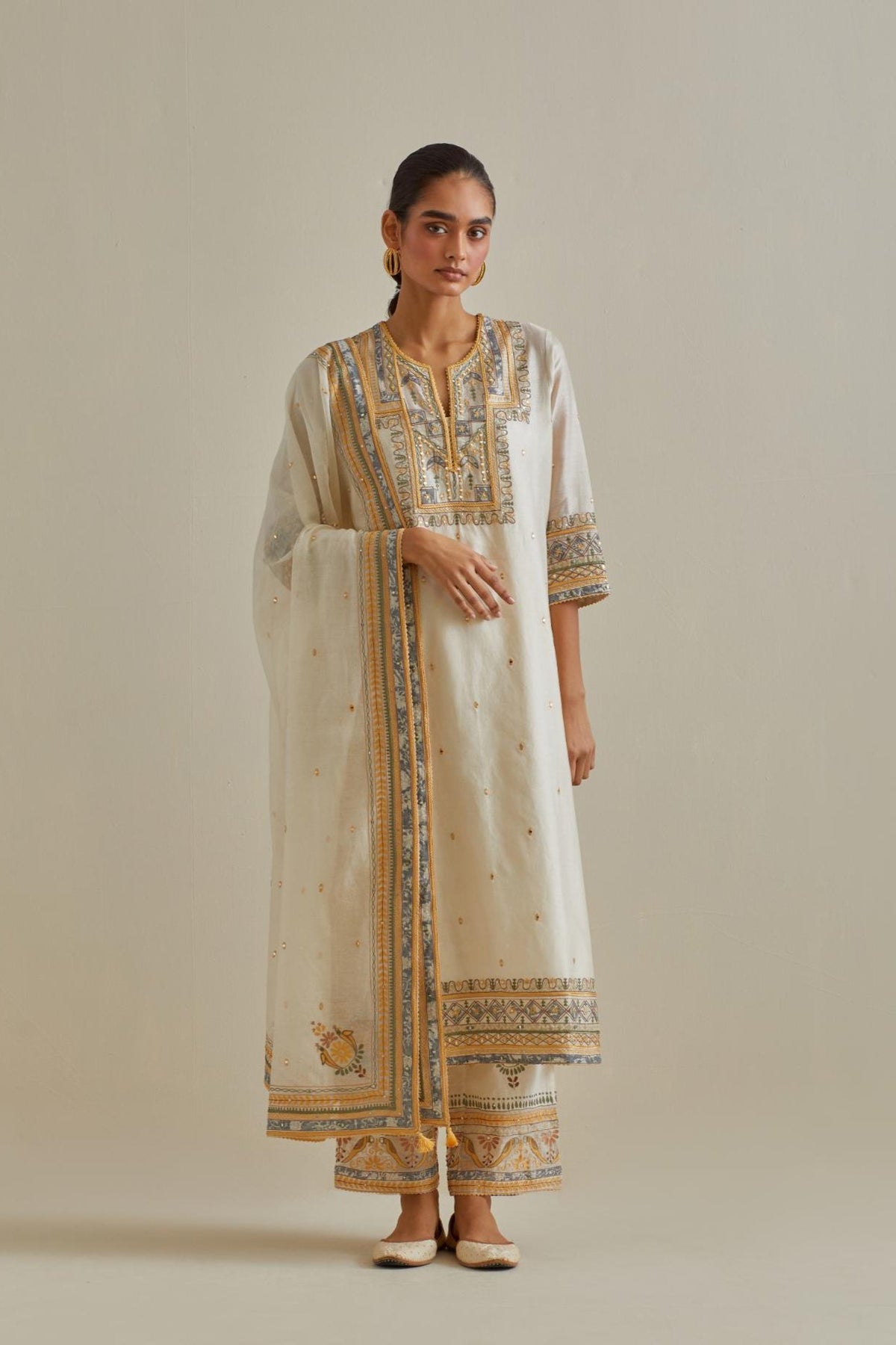 Yellow and off-white cotton chanderi straight kurta set with yoke with patchwork and silk thread embroidery highlighted with mirror, sequins, tassels and braids.