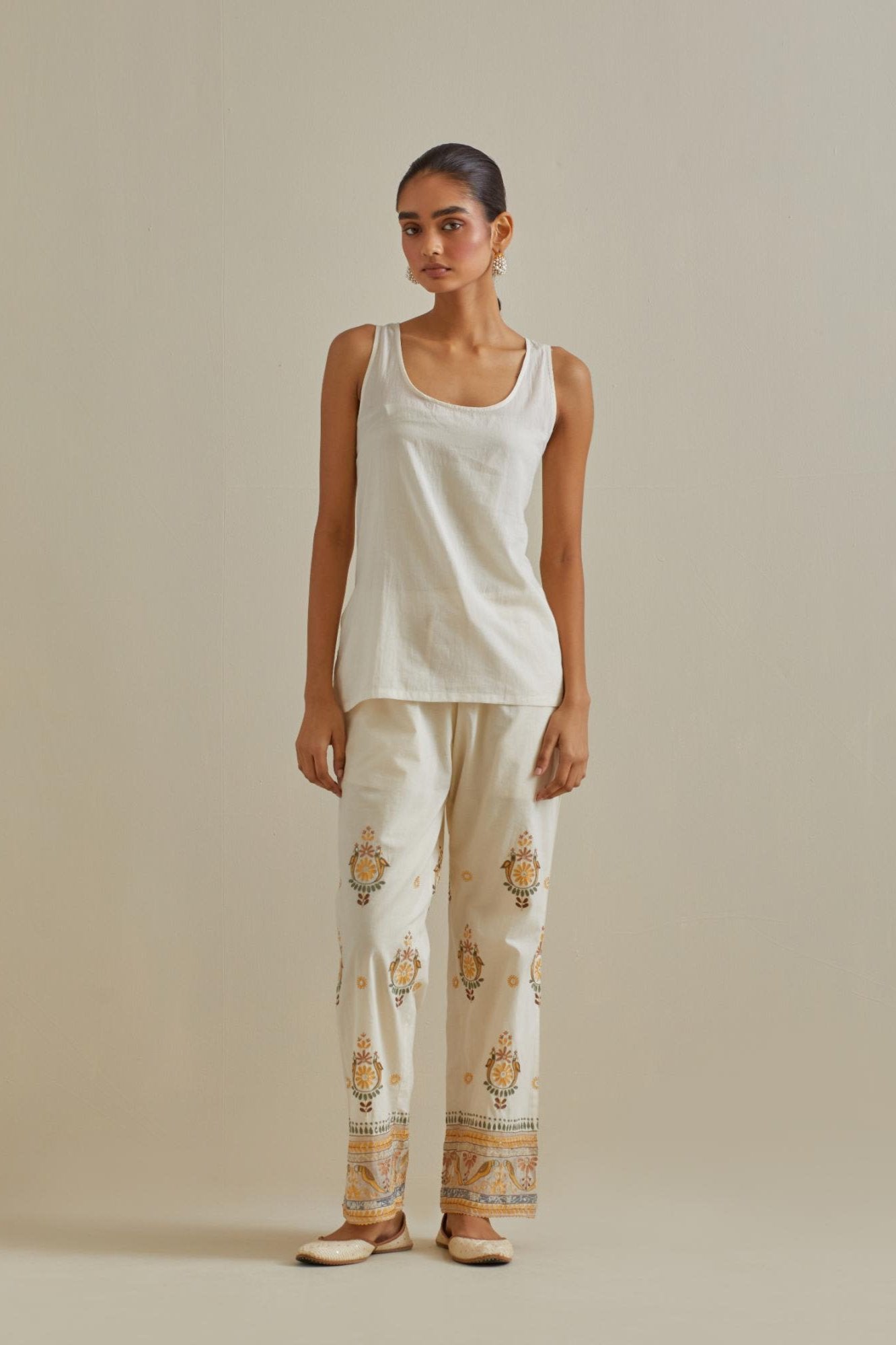 Yellow and off-white cotton chanderi embroidered short top with 3/4th sleeves, paired with off white cotton straight pants with all over multi color embroidery detailed with sequins.
