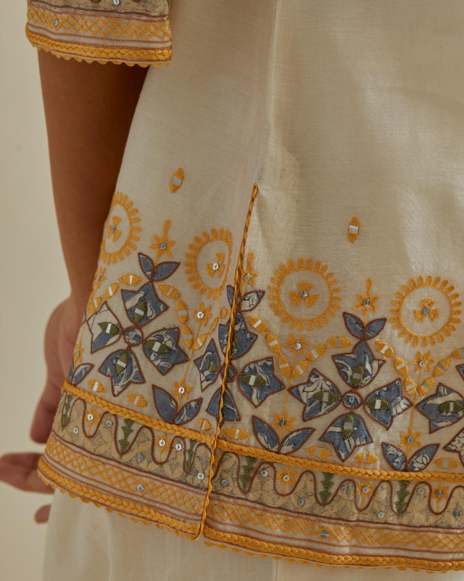 Yellow and off-white cotton chanderi embroidered short top with 3/4th sleeves, paired with off white cotton straight pants with all over multi color embroidery detailed with sequins.