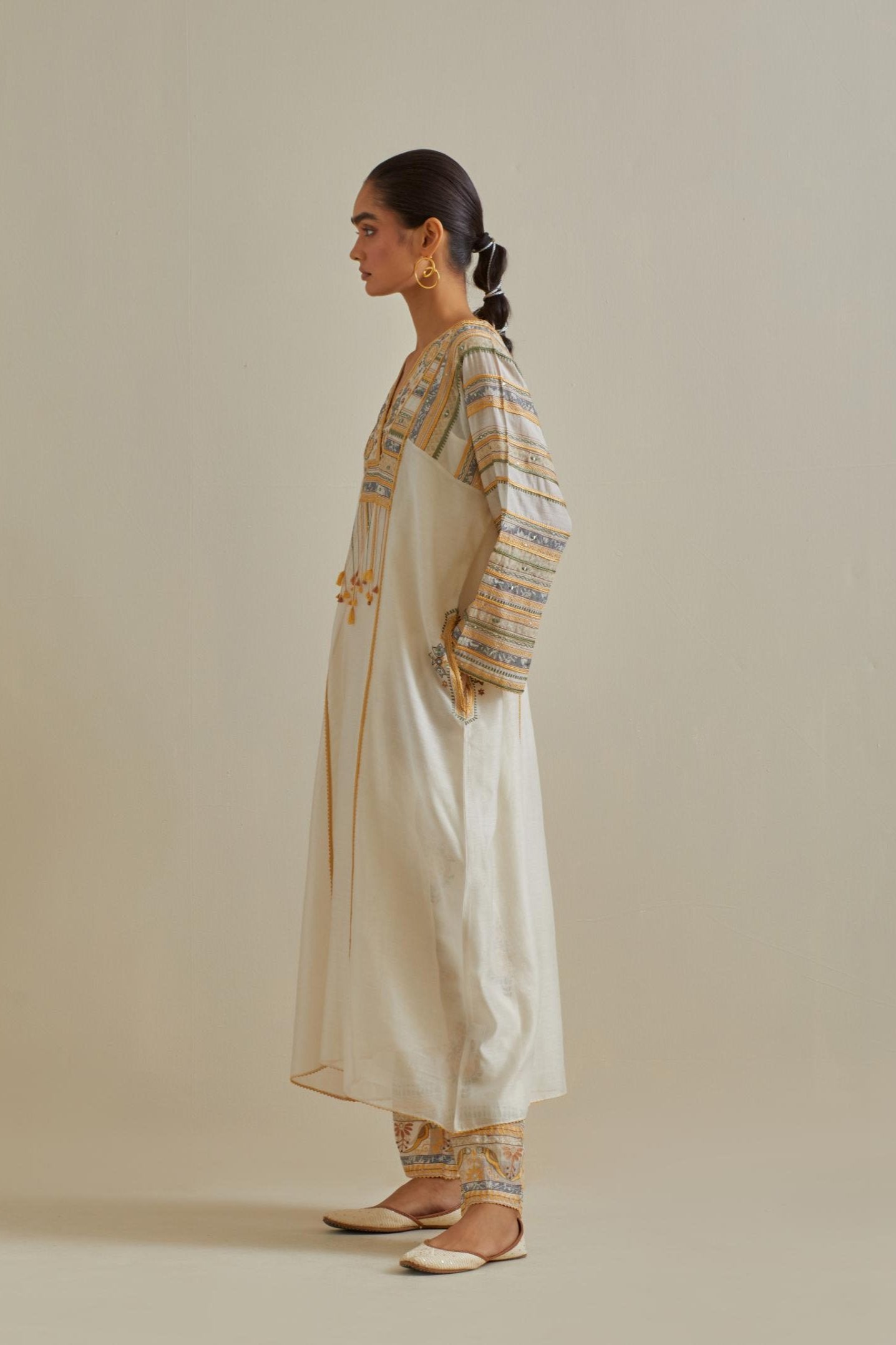Yellow and off-white cotton chanderi easy fit long kaftan detailed with patch, silk thread, mirror & sequins work, paired with off white cotton straight pants with all over multi color embroidery detailed with sequins.