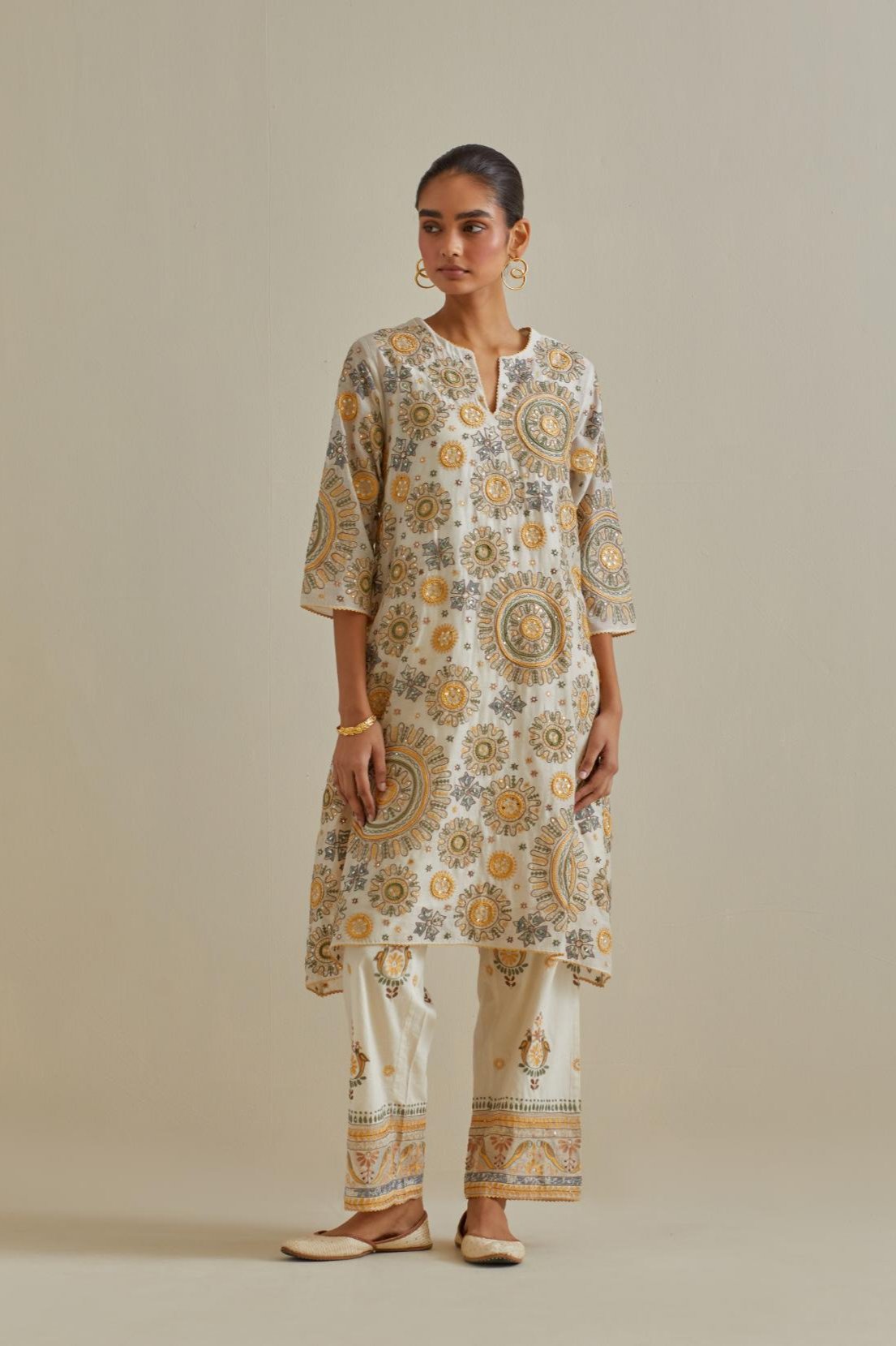 Yellow and off-white A-line cotton chanderi kurta set with all over patchwork, silk thread, mirror, tassels and sequin embroidery.