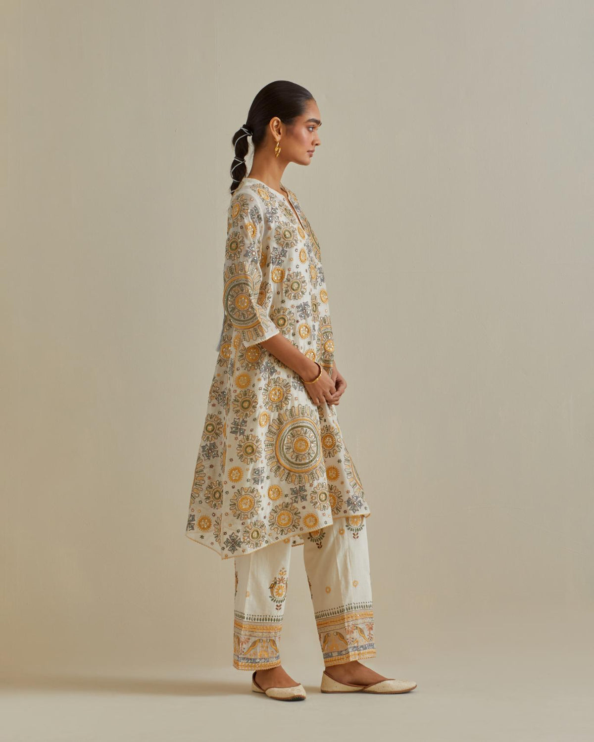 Yellow and off-white A-line cotton chanderi kurta set with all over patchwork, silk thread, mirror, tassels and sequin embroidery.