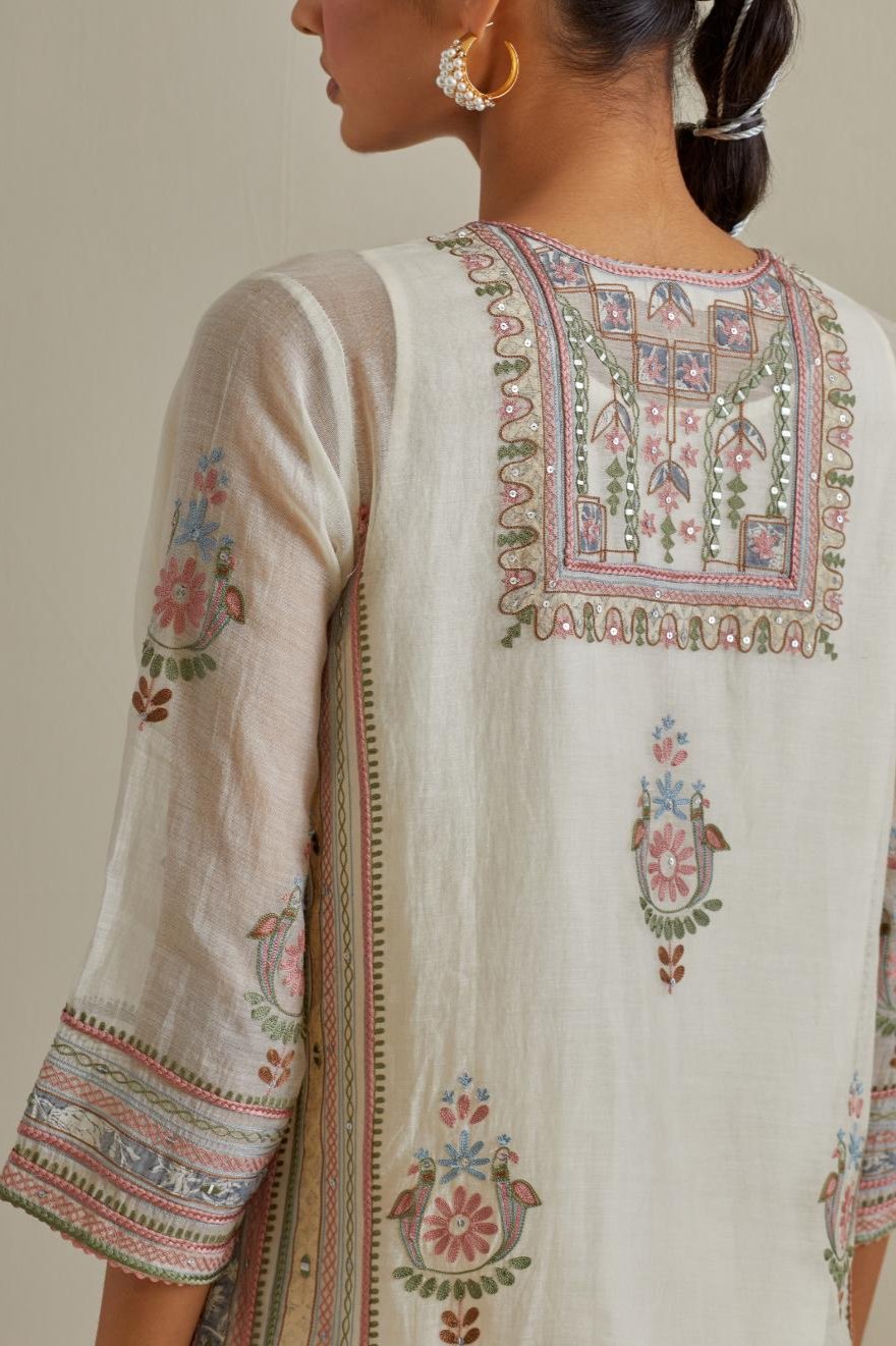 Pink and off-white cotton chanderi straight kurta set with yoke and side panels. It has allover patchwork and silk thread embroidery, highlighted with mirror, sequins, tassels and braids.