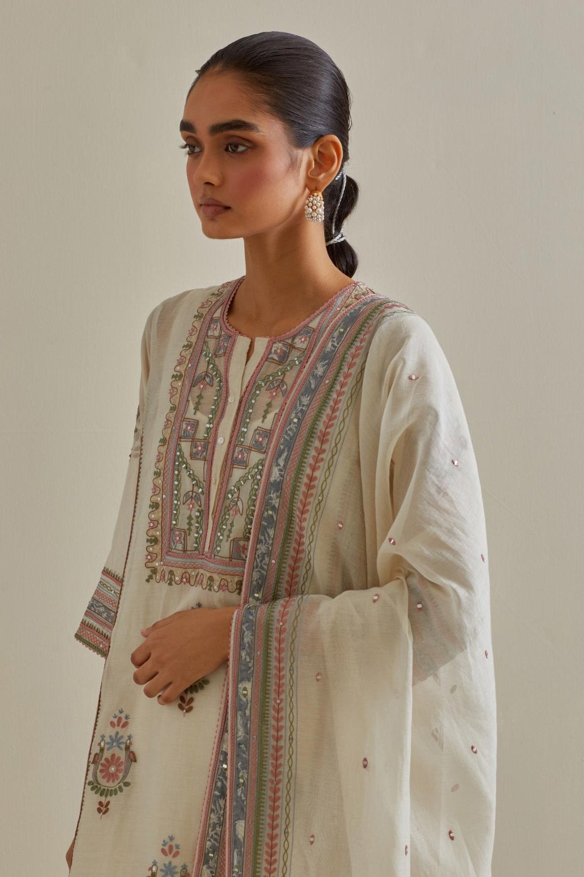 Pink and off-white cotton chanderi straight kurta set with yoke and side panels. It has allover patchwork and silk thread embroidery, highlighted with mirror, sequins, tassels and braids.