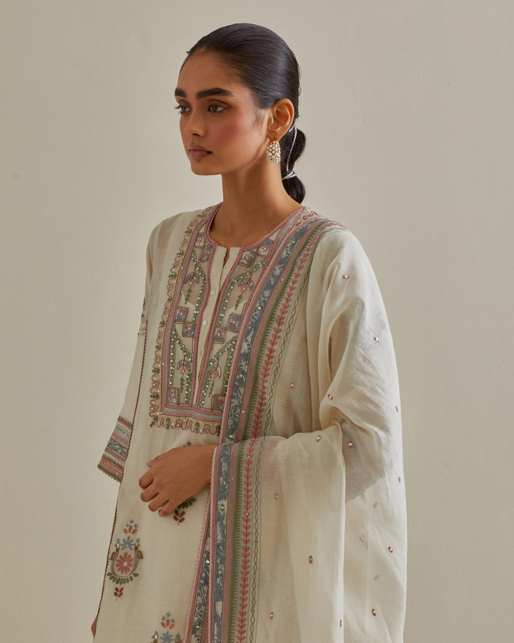 Pink and off-white cotton chanderi straight kurta set with yoke and side panels. It has allover patchwork and silk thread embroidery, highlighted with mirror, sequins, tassels and braids.