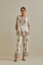 Pink and off-white cotton chanderi embroidered short top with 3/4th sleeves, paired with off white cotton straight pants with all over multi color embroidery detailed with sequins.
