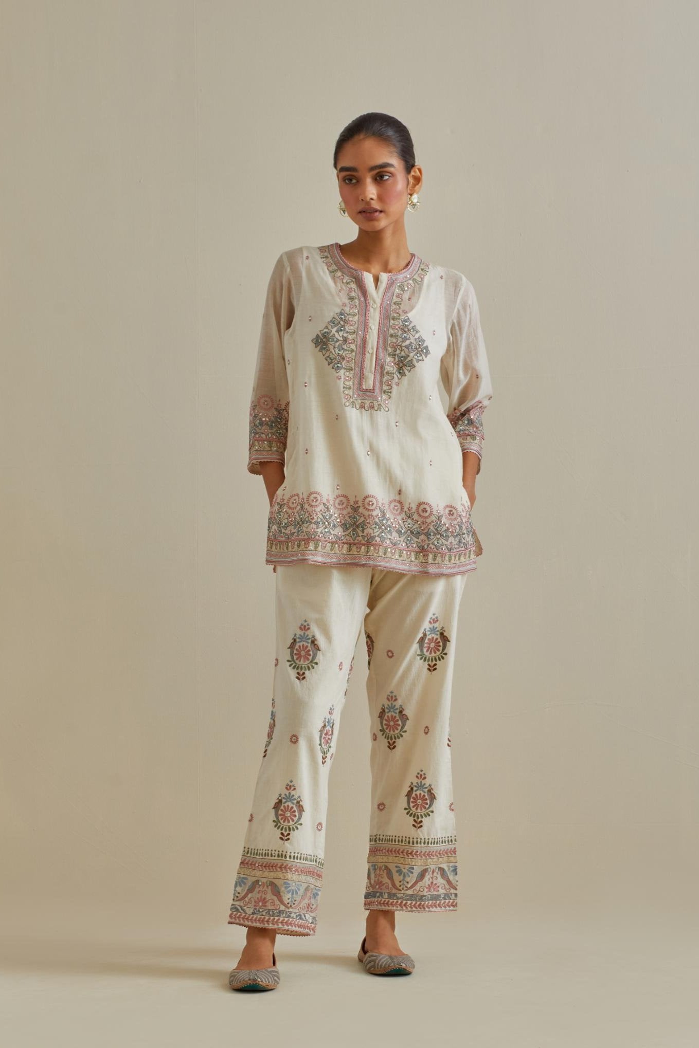 Pink and off-white cotton chanderi embroidered short top with 3/4th sleeves, paired with off white cotton straight pants with all over multi color embroidery detailed with sequins.