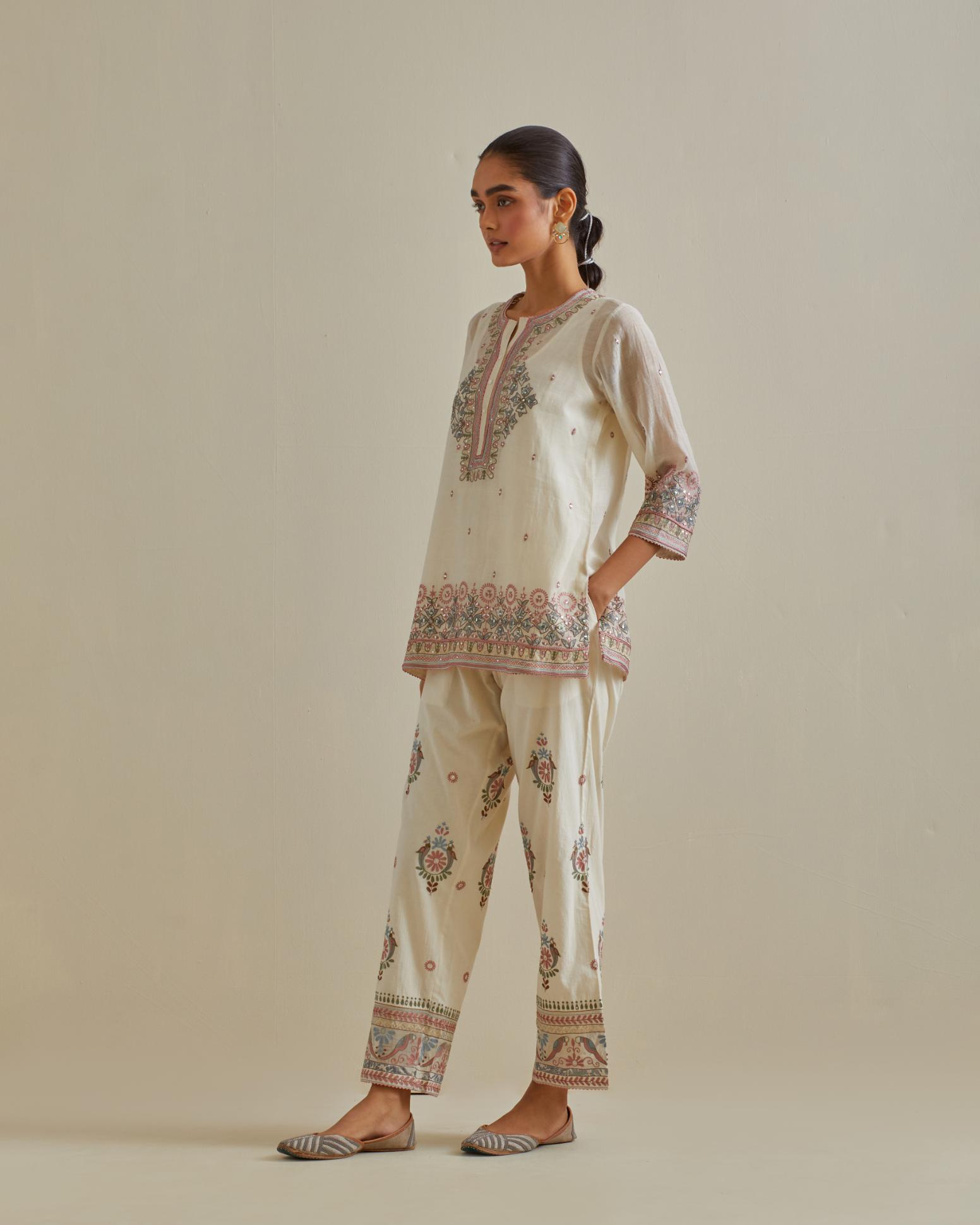 Pink and off-white cotton chanderi embroidered short top with 3/4th sleeves, paired with off white cotton straight pants with all over multi color embroidery detailed with sequins.