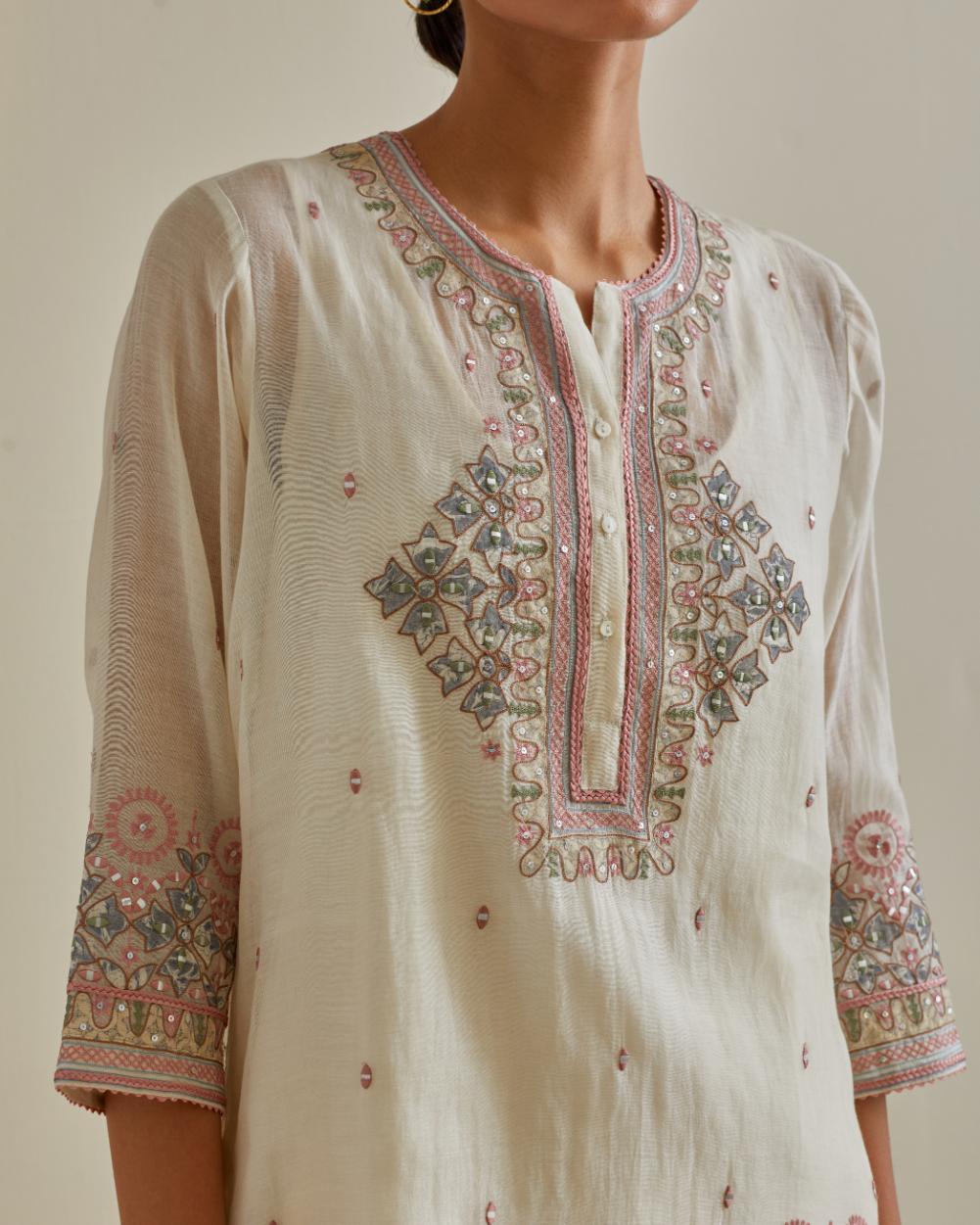 Pink and off-white cotton chanderi embroidered short top with 3/4th sleeves, paired with off white cotton straight pants with all over multi color embroidery detailed with sequins.