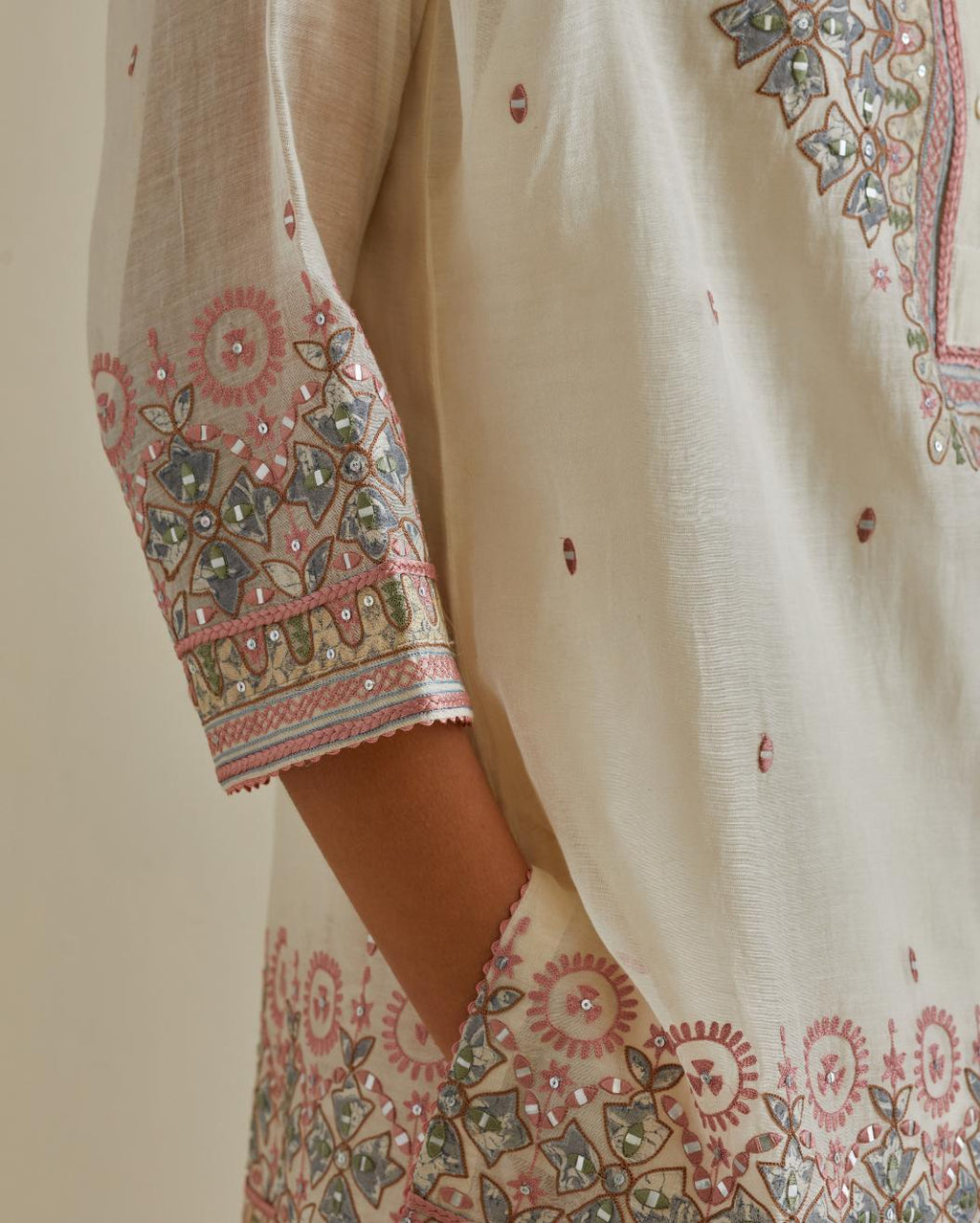 Pink and off-white cotton chanderi embroidered short top with 3/4th sleeves, paired with off white cotton straight pants with all over multi color embroidery detailed with sequins.