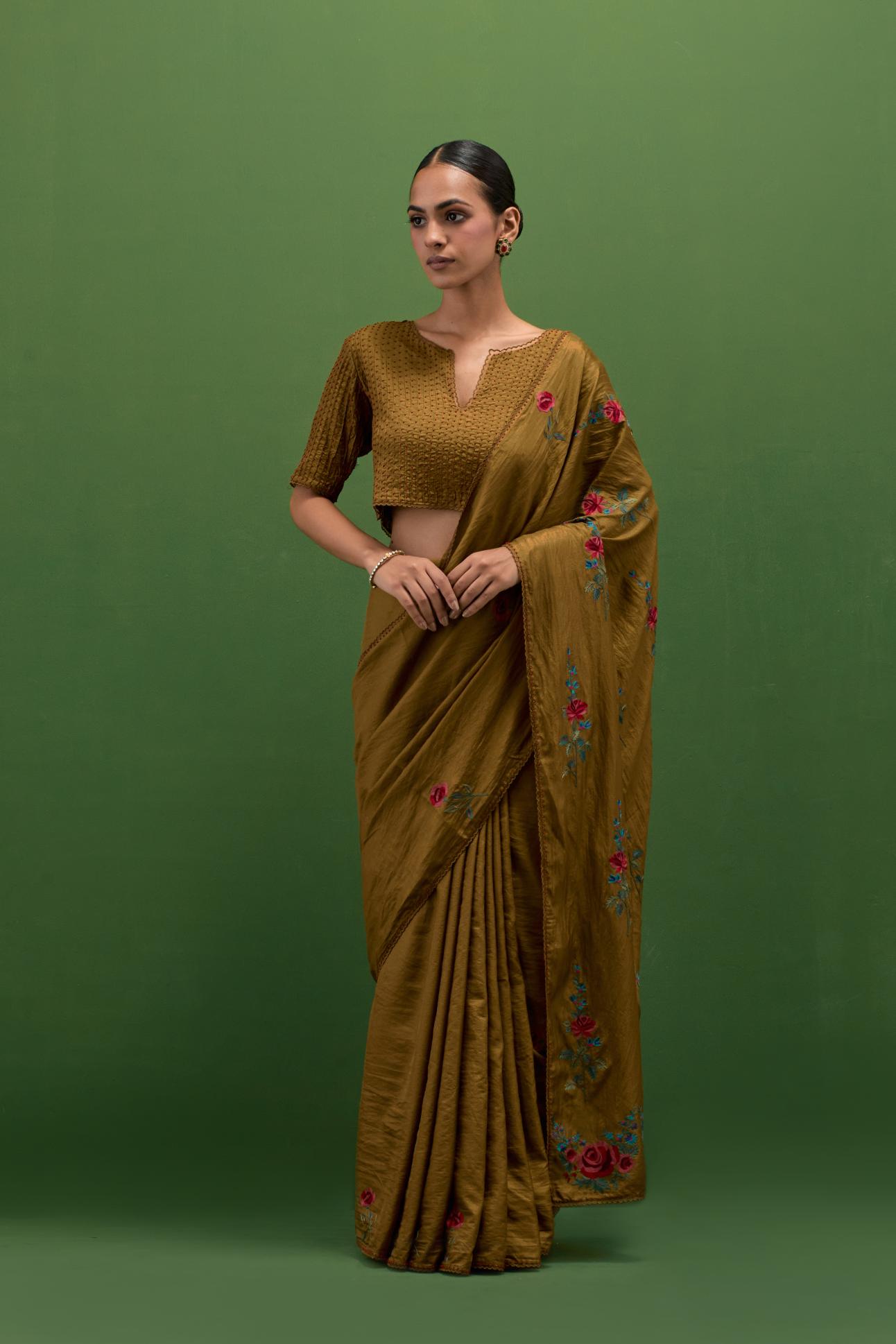 Golden olive silk saree with all-over thread embroidered roses and scalloped organza with delicate bead detail at the edges, paired with golden olive silk blouse with all-over pin tucks, highlighted with bead work.