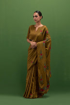 Golden olive silk saree with all-over thread embroidered roses and scalloped organza with delicate bead detail at the edges, paired with golden olive silk blouse with all-over pin tucks, highlighted with bead work.