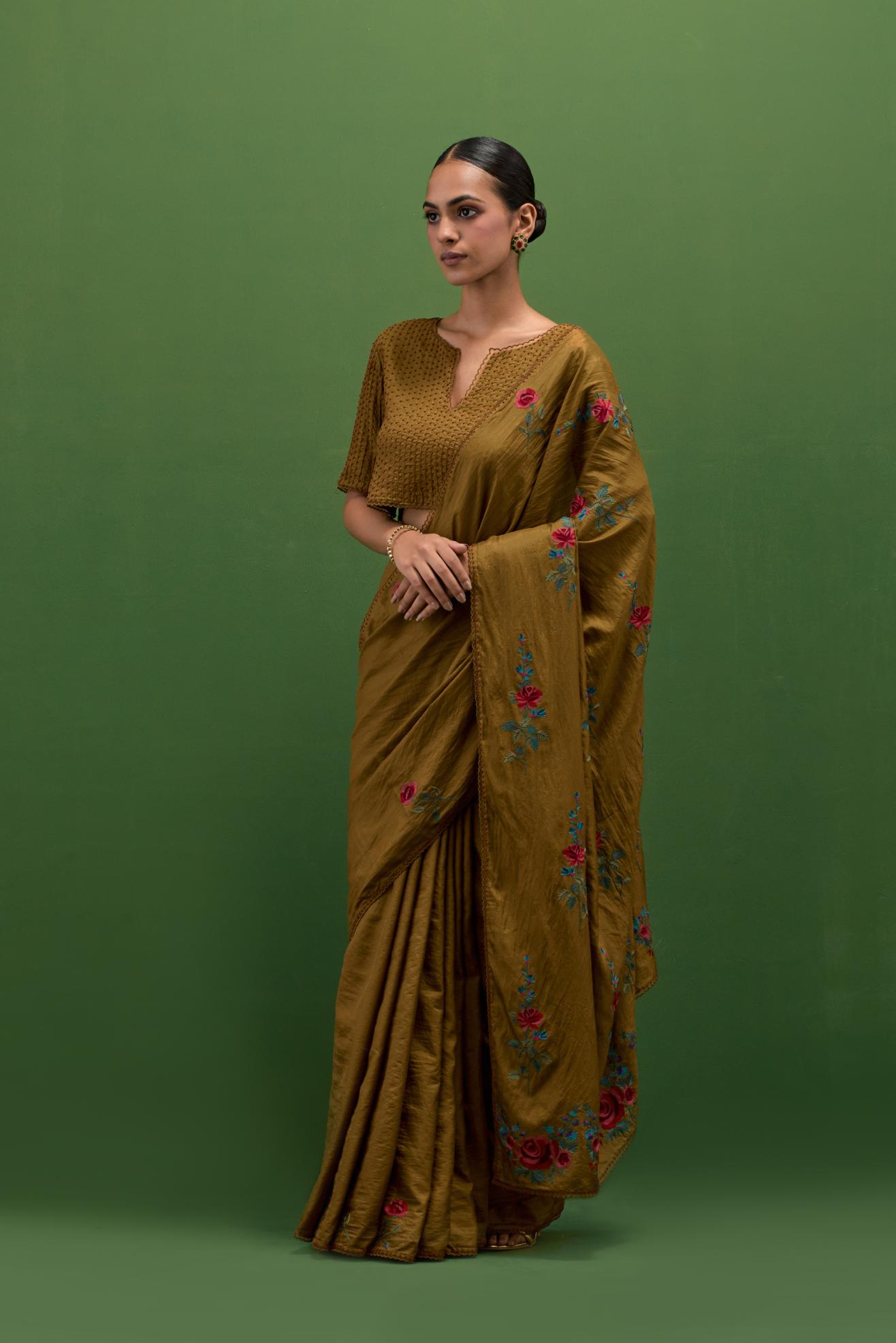 Golden olive silk saree with all-over thread embroidered roses and scalloped organza with delicate bead detail at the edges, paired with golden olive silk blouse with all-over pin tucks, highlighted with bead work.