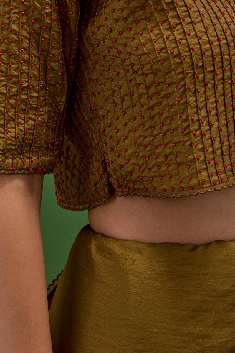 Golden olive silk saree with all-over thread embroidered roses and scalloped organza with delicate bead detail at the edges, paired with golden olive silk blouse with all-over pin tucks, highlighted with bead work.