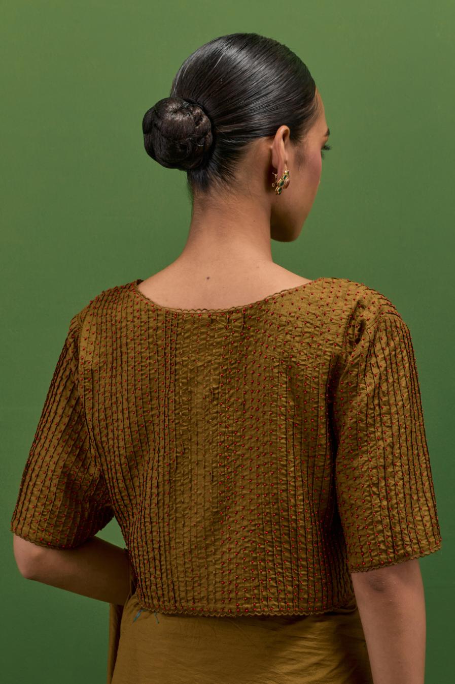 Golden olive silk blouse with all-over pin tucks, highlighted with bead work.