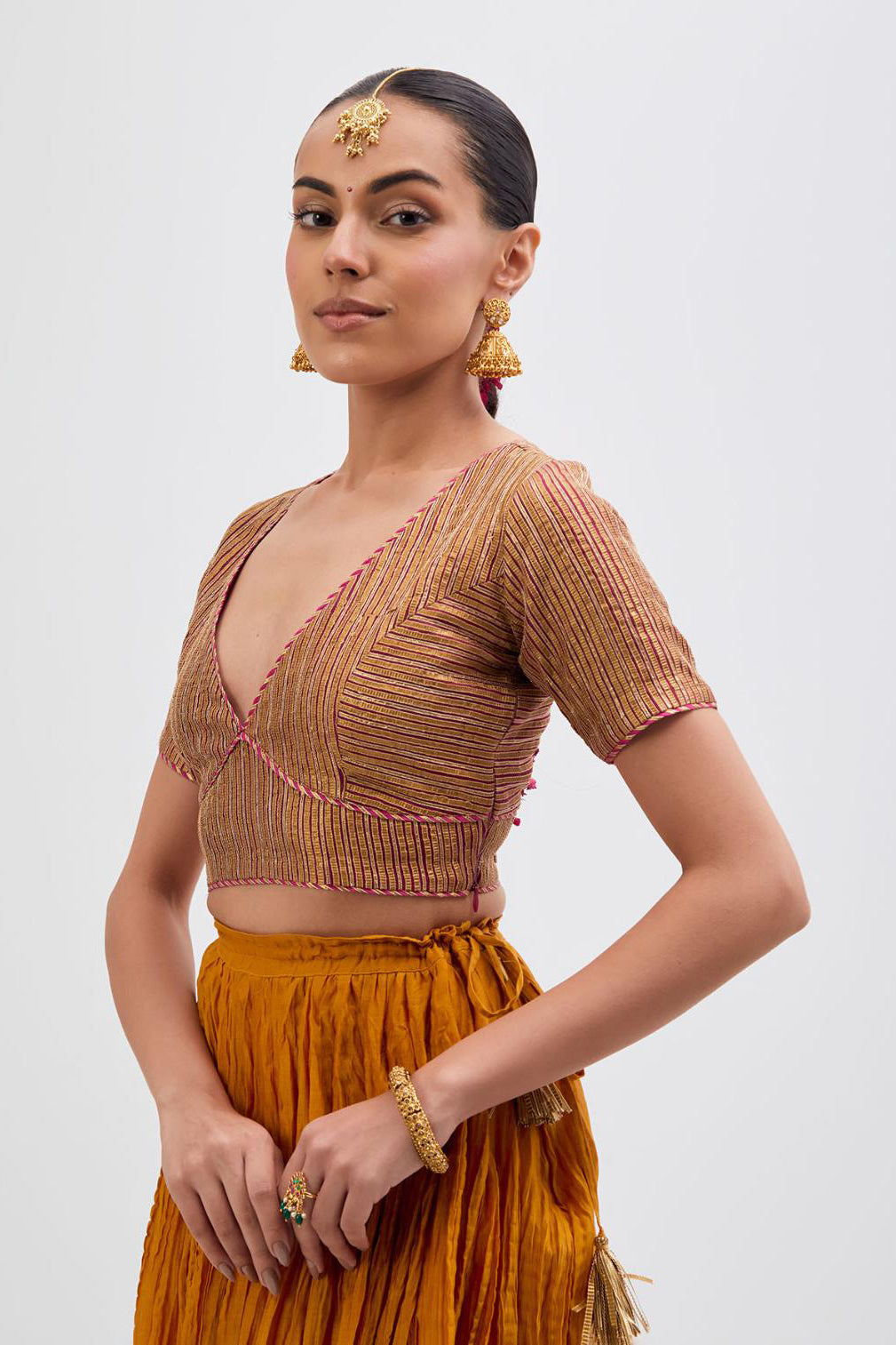 Yellow Silk Chanderi choli set with all-over gold gota work. It has a deep V neckline in the front, short sleeves and side zip.