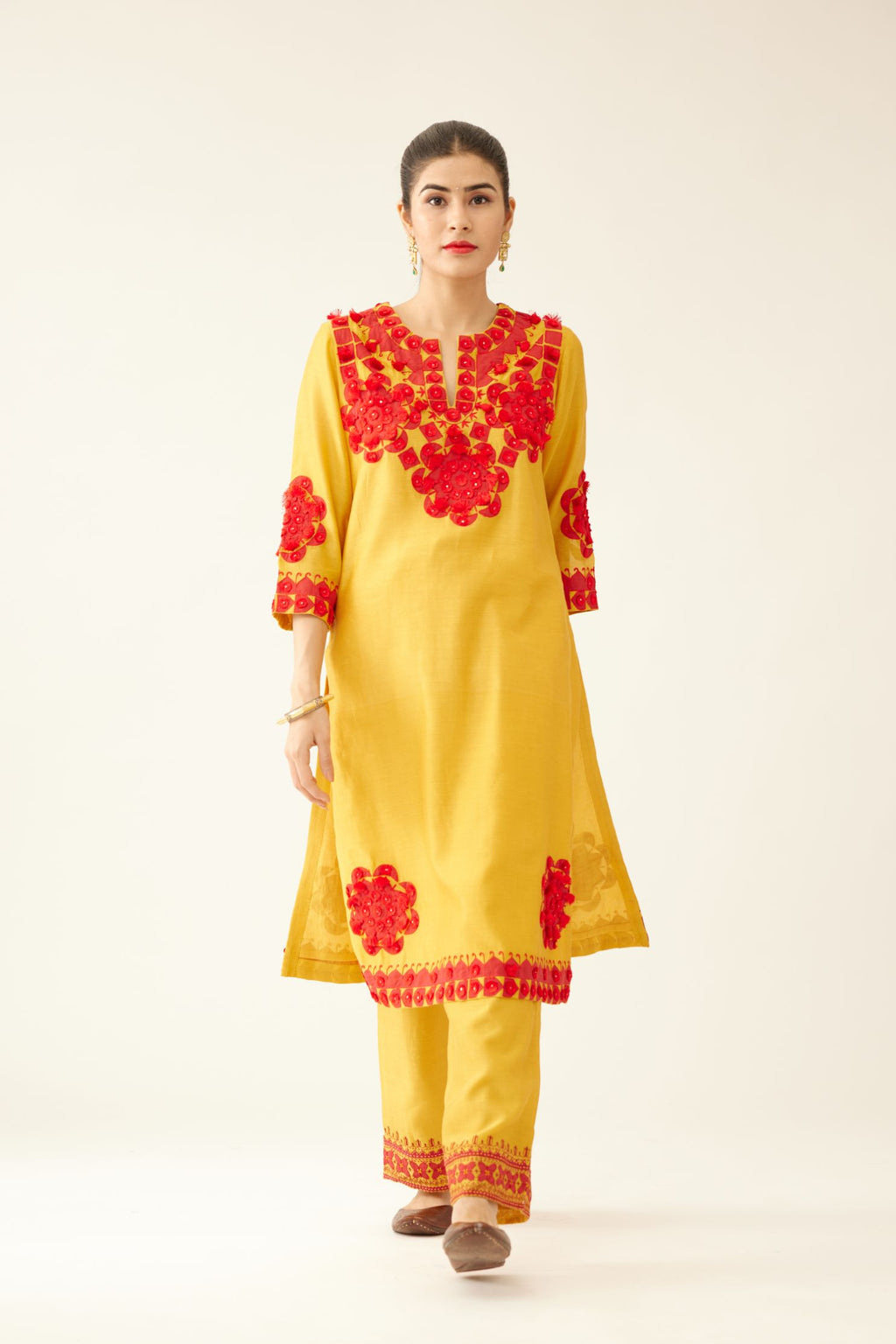 Golden yellow silk chanderi mid length straight kurta set, highlighted with all-over contrast applique, tassels and sequins.
