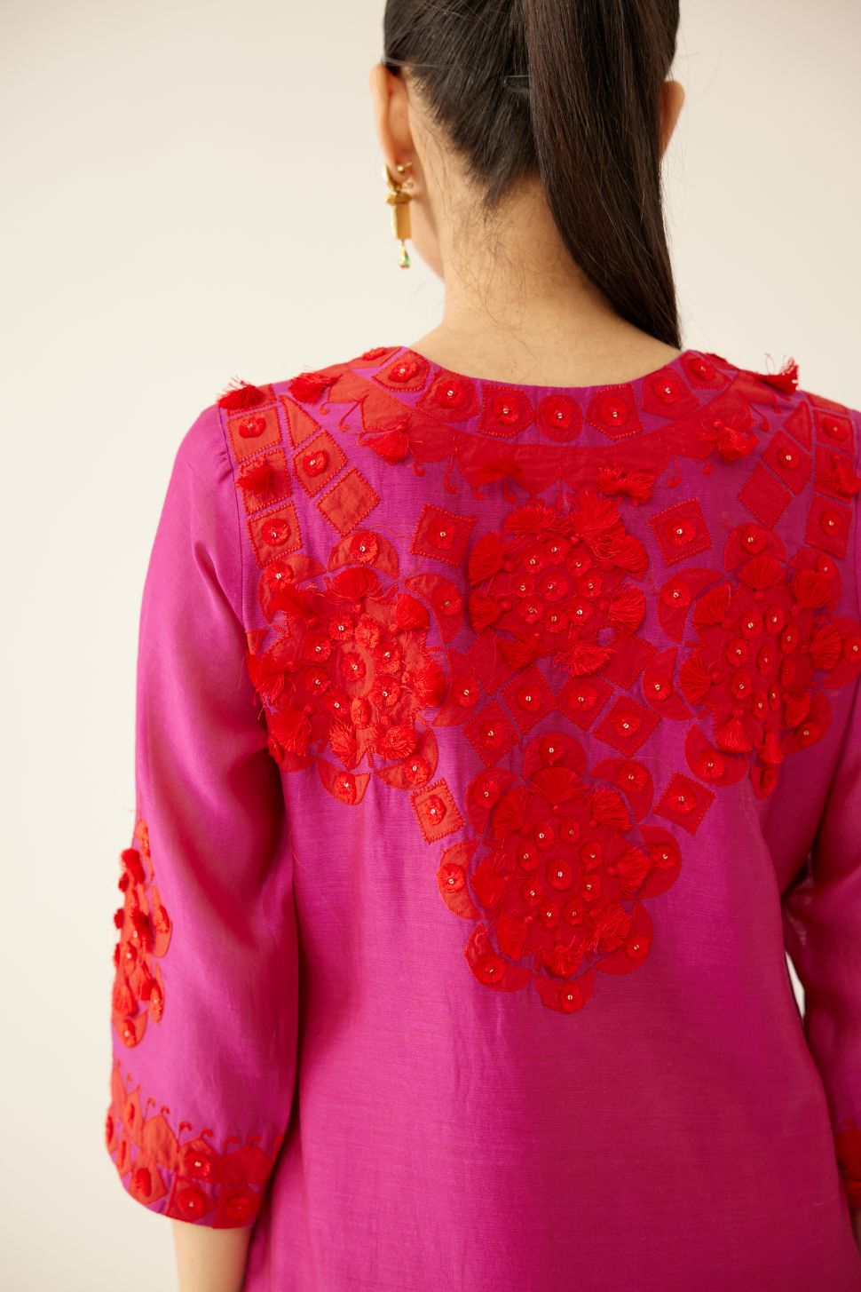 Fuchsia silk chanderi mid length straight kurta set, highlighted with all-over contrast applique, tassels and sequins.