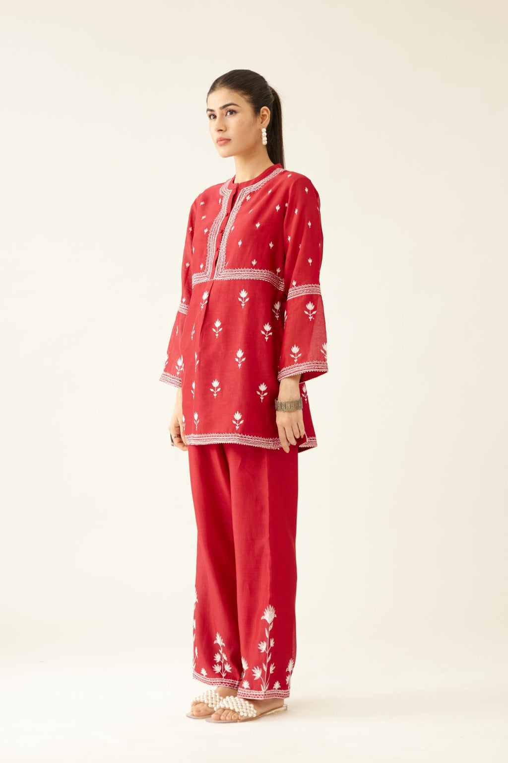 Red silk chanderi short top with all-over off white silk thread embroidery, paired with red silk chanderi straight pants with off white silk thread embroidery at hem.