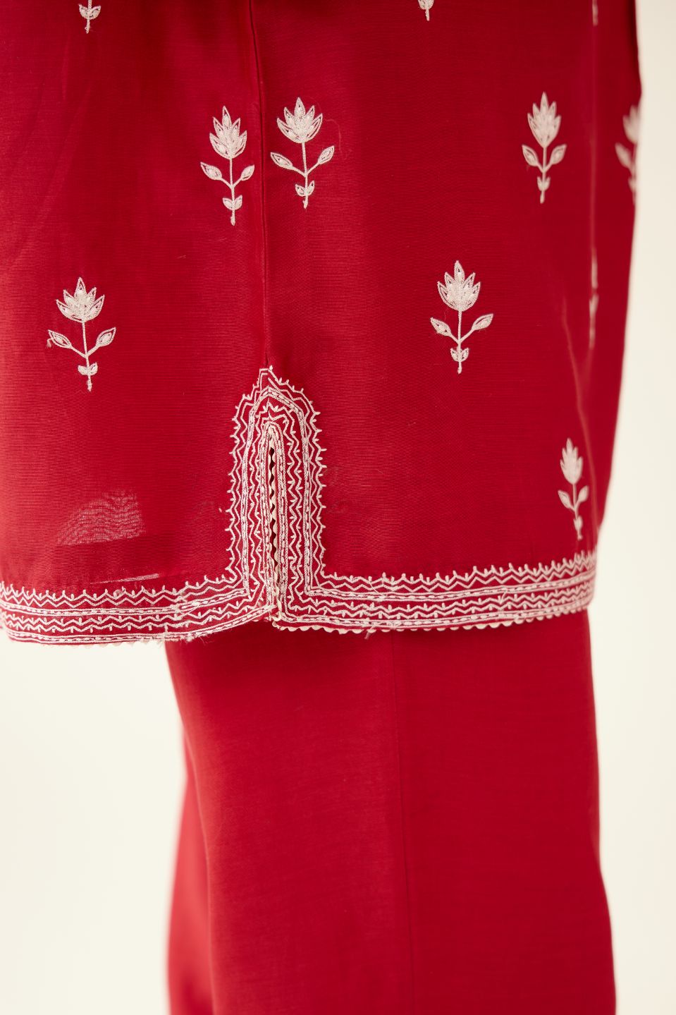 Red silk chanderi short top with all-over off white silk thread embroidery, paired with red silk chanderi straight pants with off white silk thread embroidery at hem.