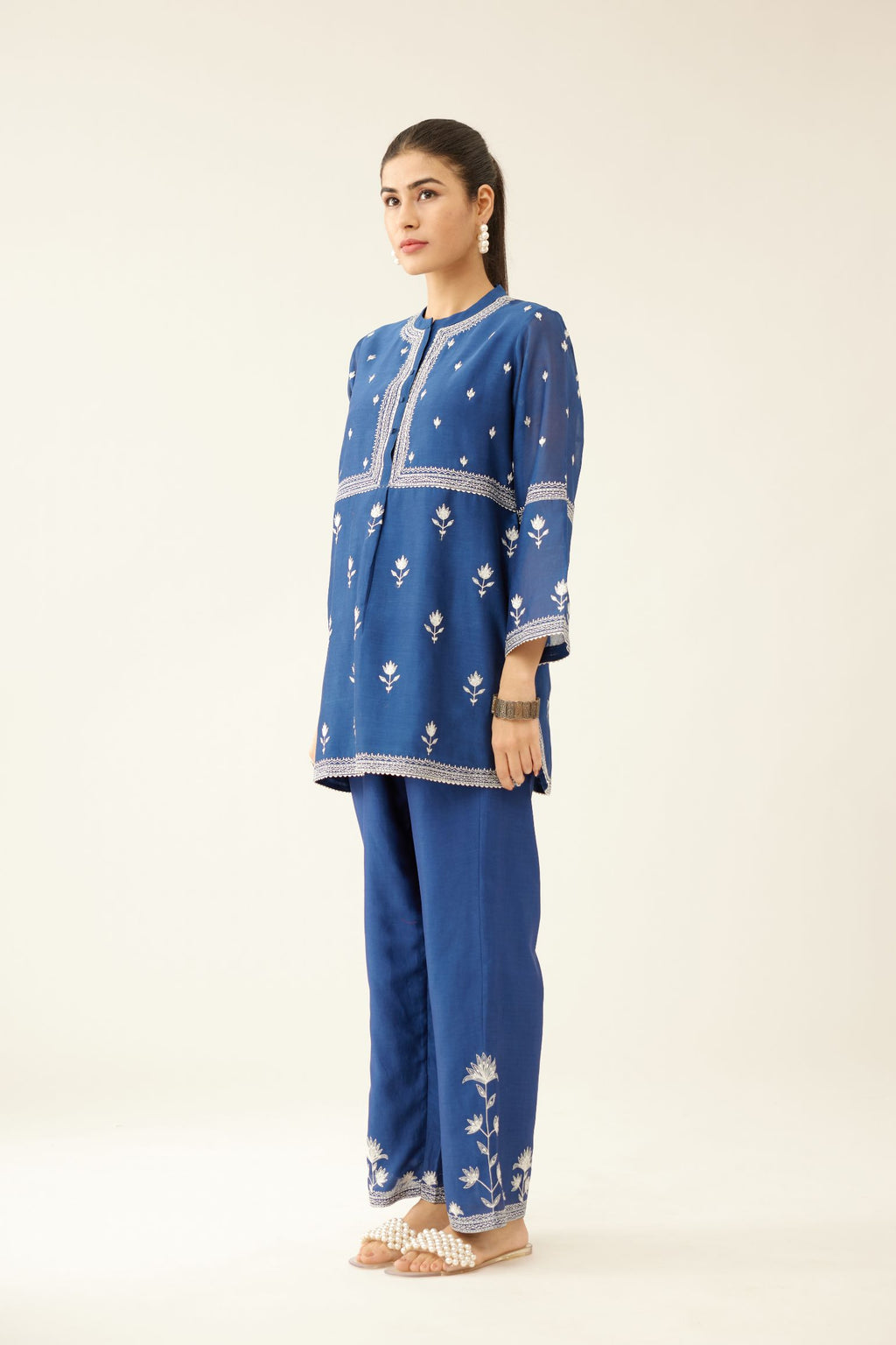 Blue silk chanderi short top with all-over off white silk thread embroidery, paired with blue silk chanderi straight pants with off white silk thread embroidery at hem.