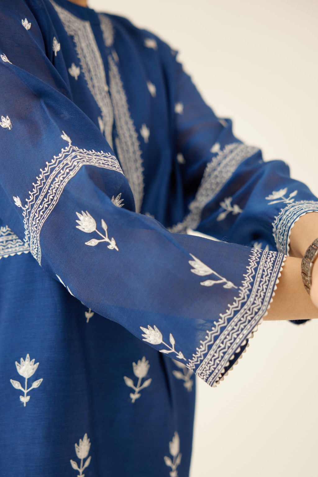 Blue silk chanderi short top with all-over off white silk thread embroidery, paired with blue silk chanderi straight pants with off white silk thread embroidery at hem.