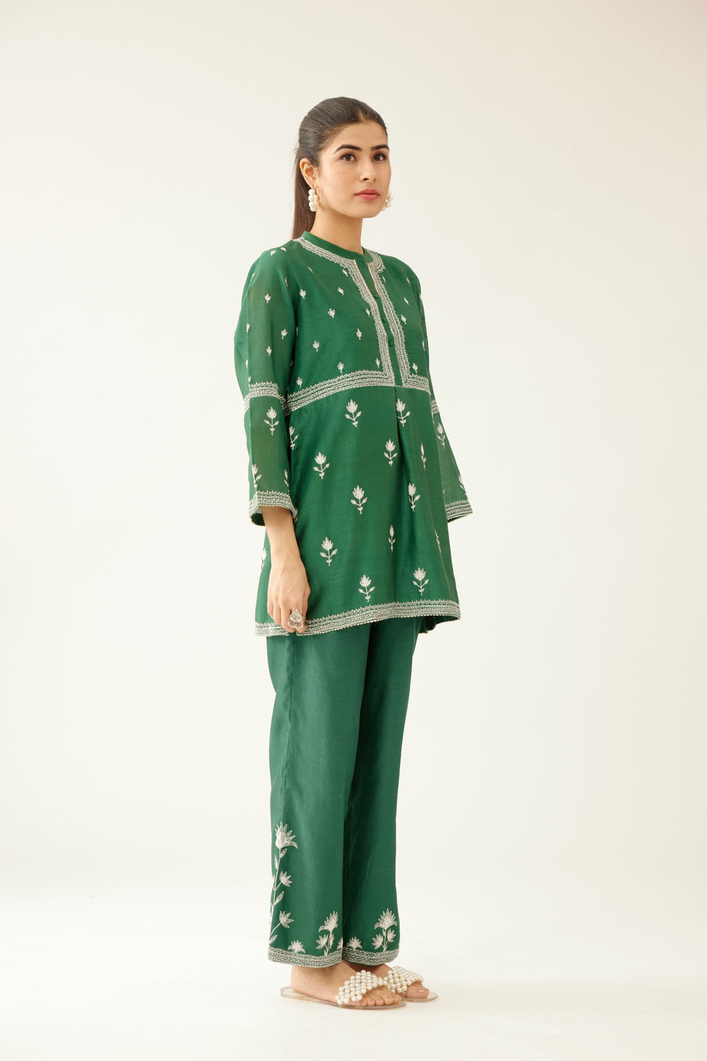 Green silk chanderi short top with all-over off white silk thread embroidery, paired with green silk chanderi straight pants with off white silk thread embroidery at hem.