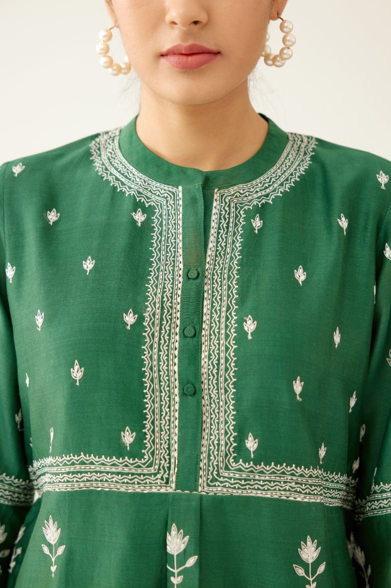 Green silk chanderi short top with all-over off white silk thread embroidery, paired with green silk chanderi straight pants with off white silk thread embroidery at hem.