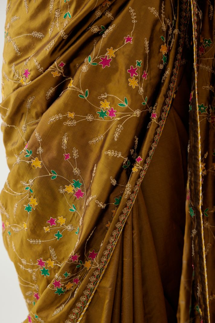 Golden olive silk saree set, detailed with all over delicate dori and silk thread embroidery work, paired with raspberry silk blouse with princess seams and all-over delicate dori and silk thread embroidered.