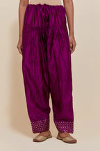Purple silk farshi salwar with hand-embroidered gold sequin work in a broad border at the hem.