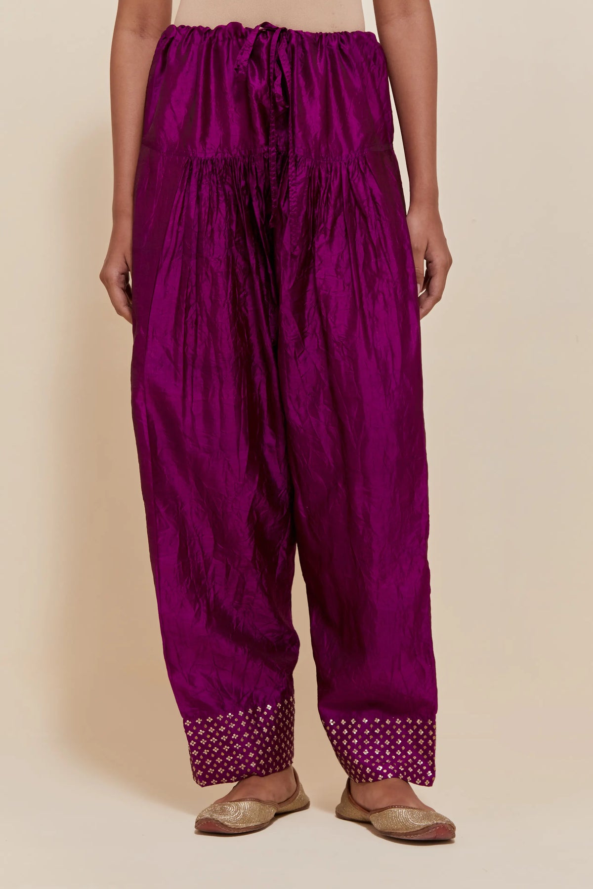 Purple silk farshi salwar with hand-embroidered gold sequin work in a broad border at the hem.