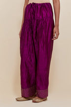Purple silk farshi salwar with hand-embroidered gold sequin work in a broad border at the hem.