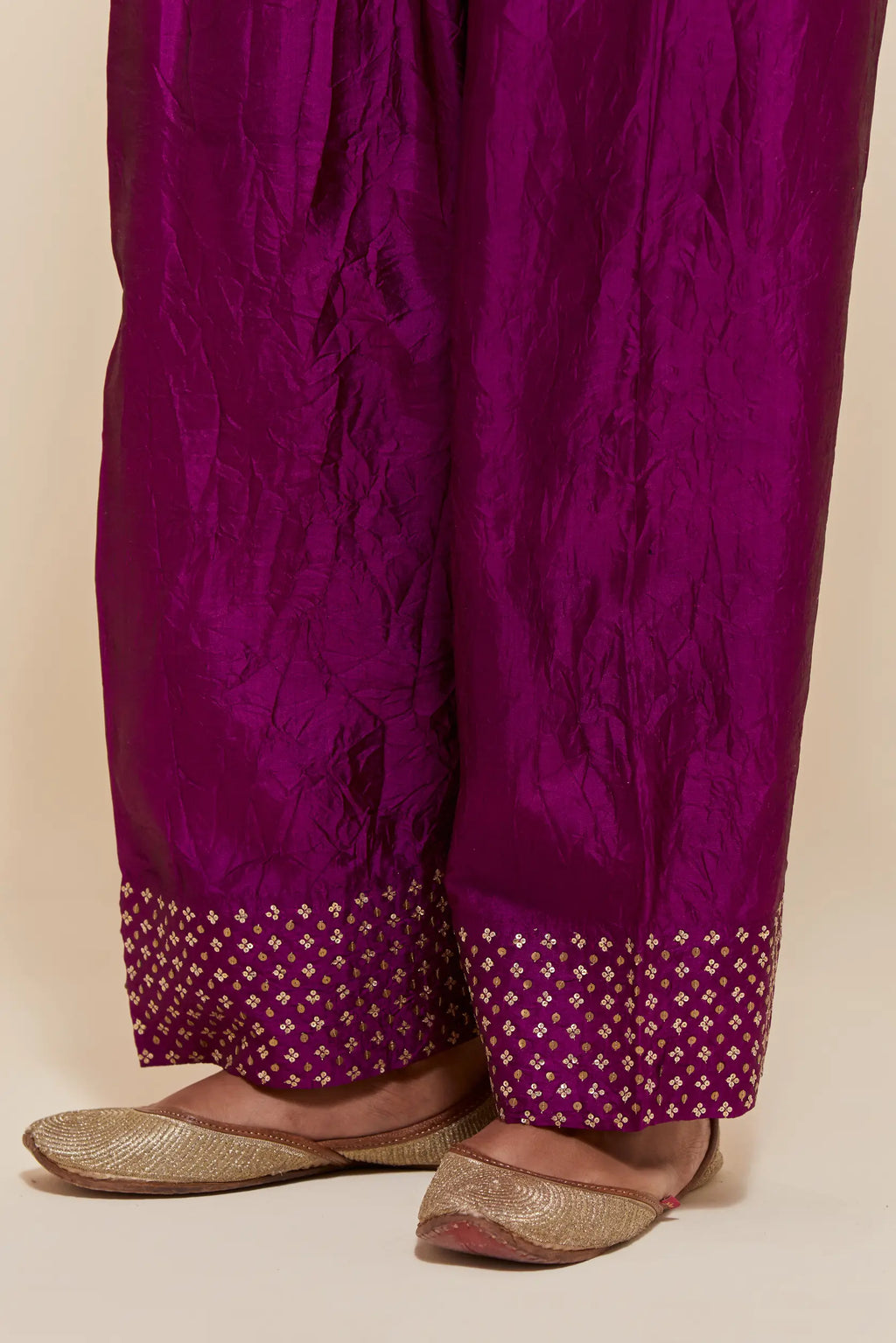 Purple silk farshi salwar with hand-embroidered gold sequin work in a broad border at the hem.