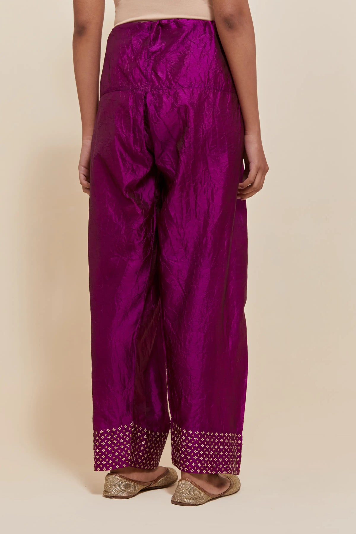 Purple silk farshi salwar with hand-embroidered gold sequin work in a broad border at the hem.