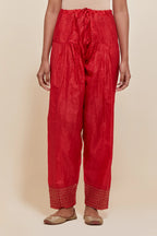 Red silk salwar with hand-embroidered gold sequin work in a broad border at the hem.