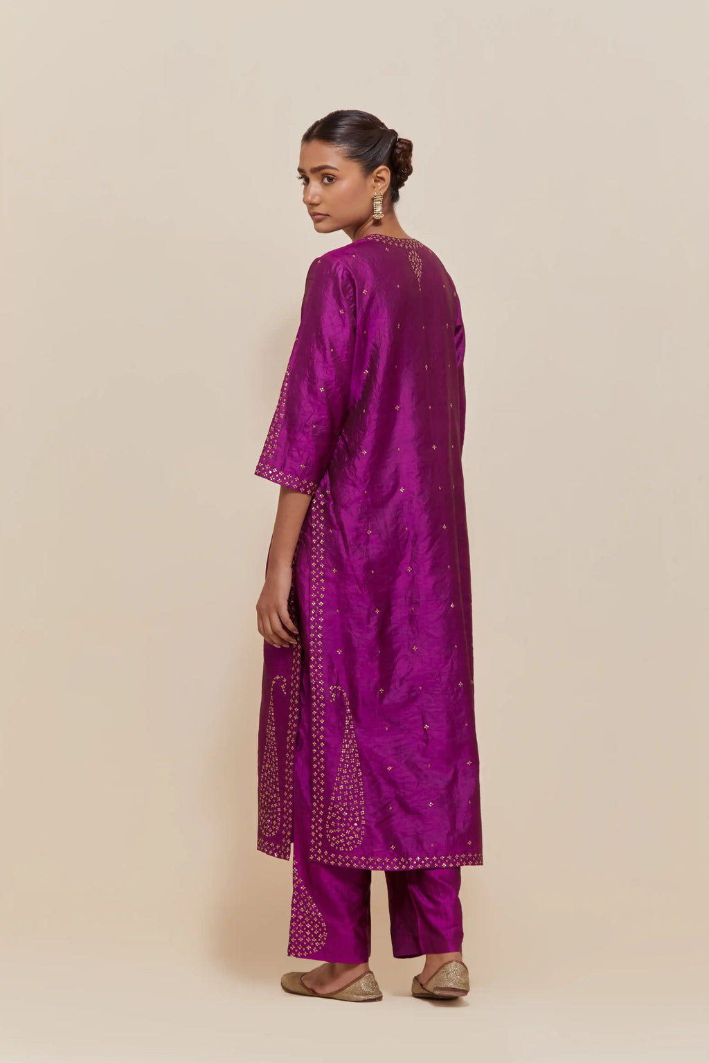Purple silk straight kurta set with hand-embroidered paisley motifs with delicate gold sequins work at neck, hem, and sleeves, with narrow borders along the edges.