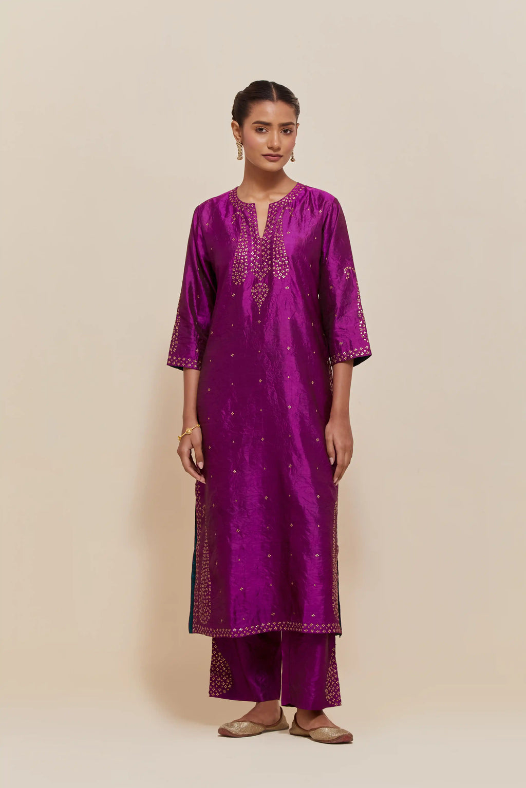 Purple silk straight kurta set with hand-embroidered paisley motifs with delicate gold sequins work at neck, hem, and sleeves, with narrow borders along the edges.