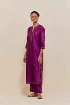 Purple silk straight kurta set with hand-embroidered paisley motifs with delicate gold sequins work at neck, hem, and sleeves, with narrow borders along the edges.