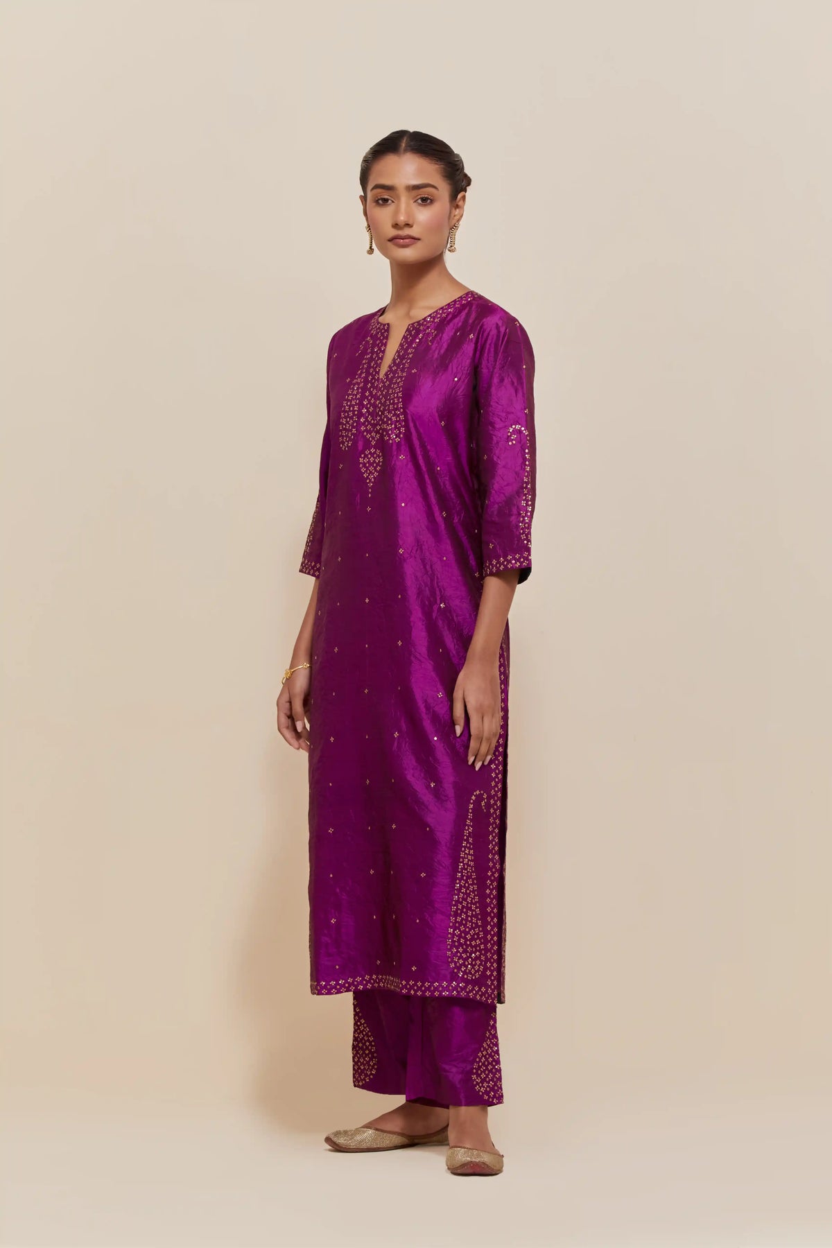 Purple silk straight kurta set with hand-embroidered paisley motifs with delicate gold sequins work at neck, hem, and sleeves, with narrow borders along the edges.