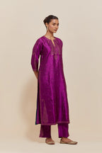 Purple silk straight kurta set with hand-embroidered paisley motifs with delicate gold sequins work at neck, hem, and sleeves, with narrow borders along the edges.