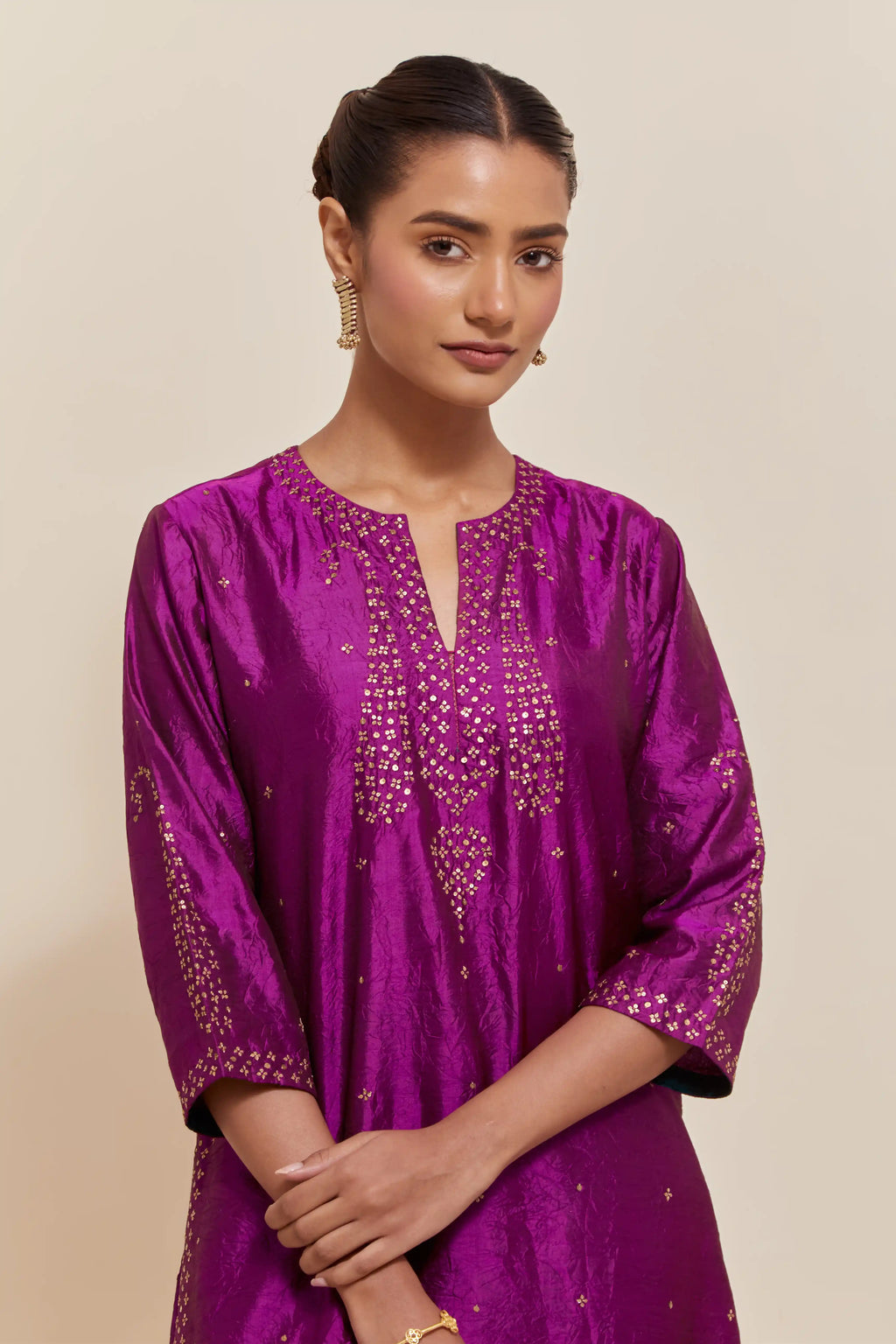 Purple silk straight kurta set with hand-embroidered paisley motifs with delicate gold sequins work at neck, hem, and sleeves, with narrow borders along the edges.