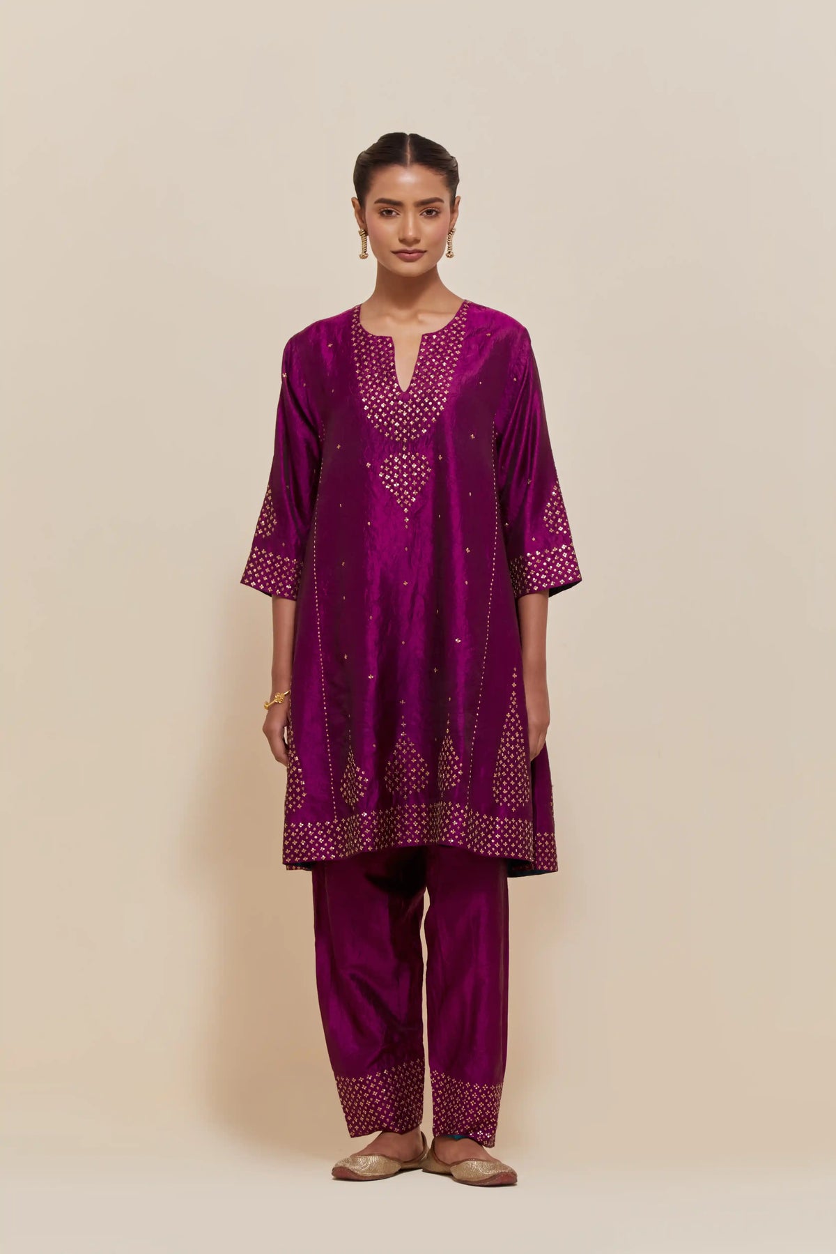 Purple silk short kalidar kurta set, with hand embroidered sequins at neck, hem and sleeve edges, highlighted with scattered gold sequins embellishments all-over.