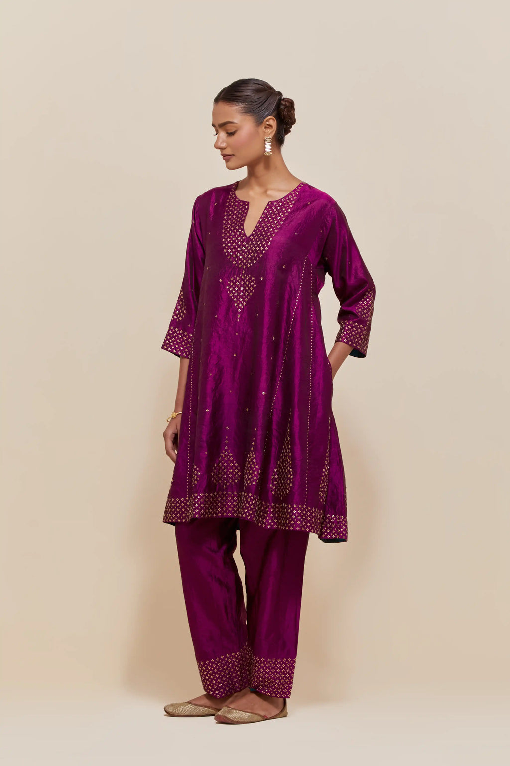 Purple silk short kalidar kurta set, with hand embroidered sequins at neck, hem and sleeve edges, highlighted with scattered gold sequins embellishments all-over.