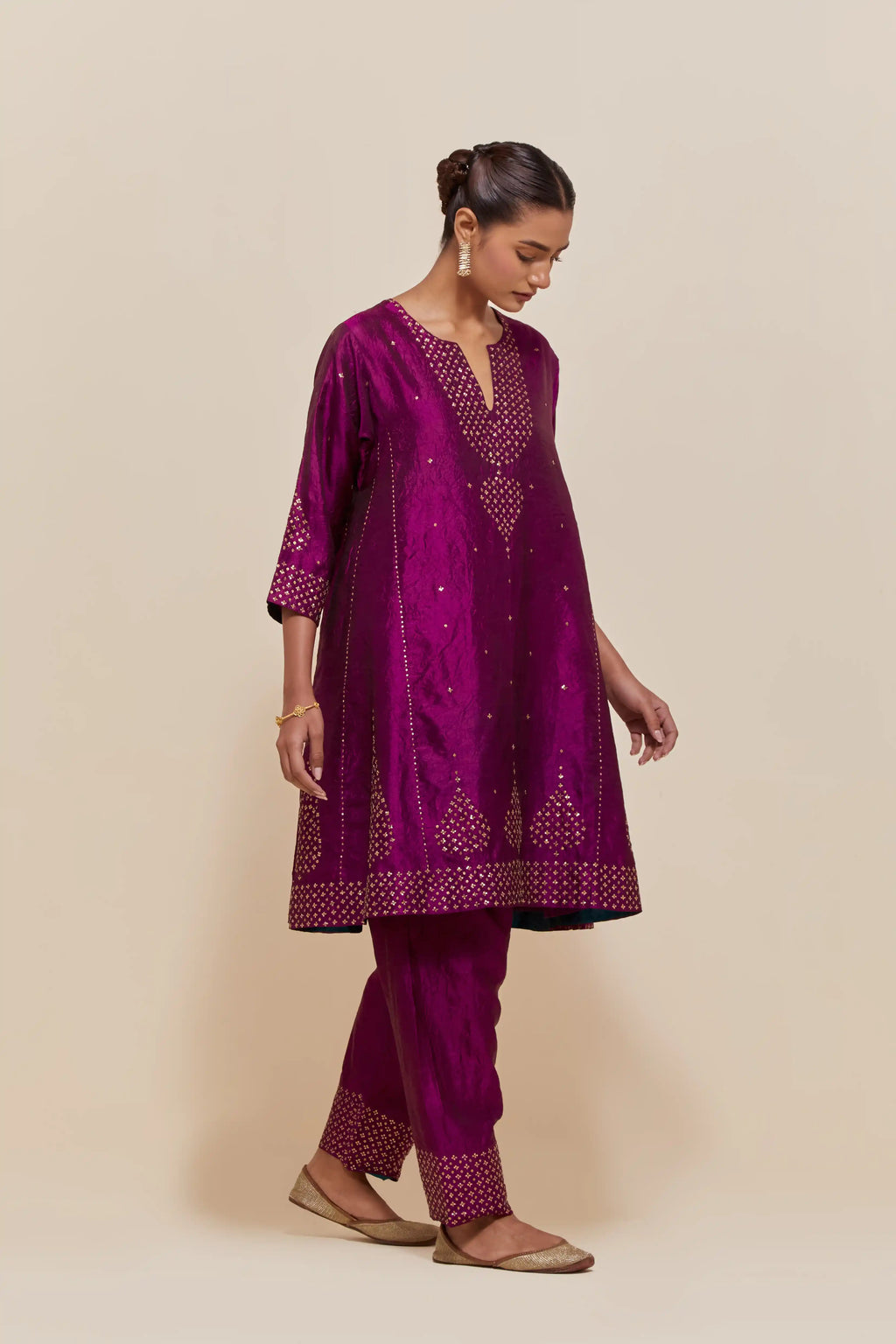 Purple silk short kalidar kurta set, with hand embroidered sequins at neck, hem and sleeve edges, highlighted with scattered gold sequins embellishments all-over.