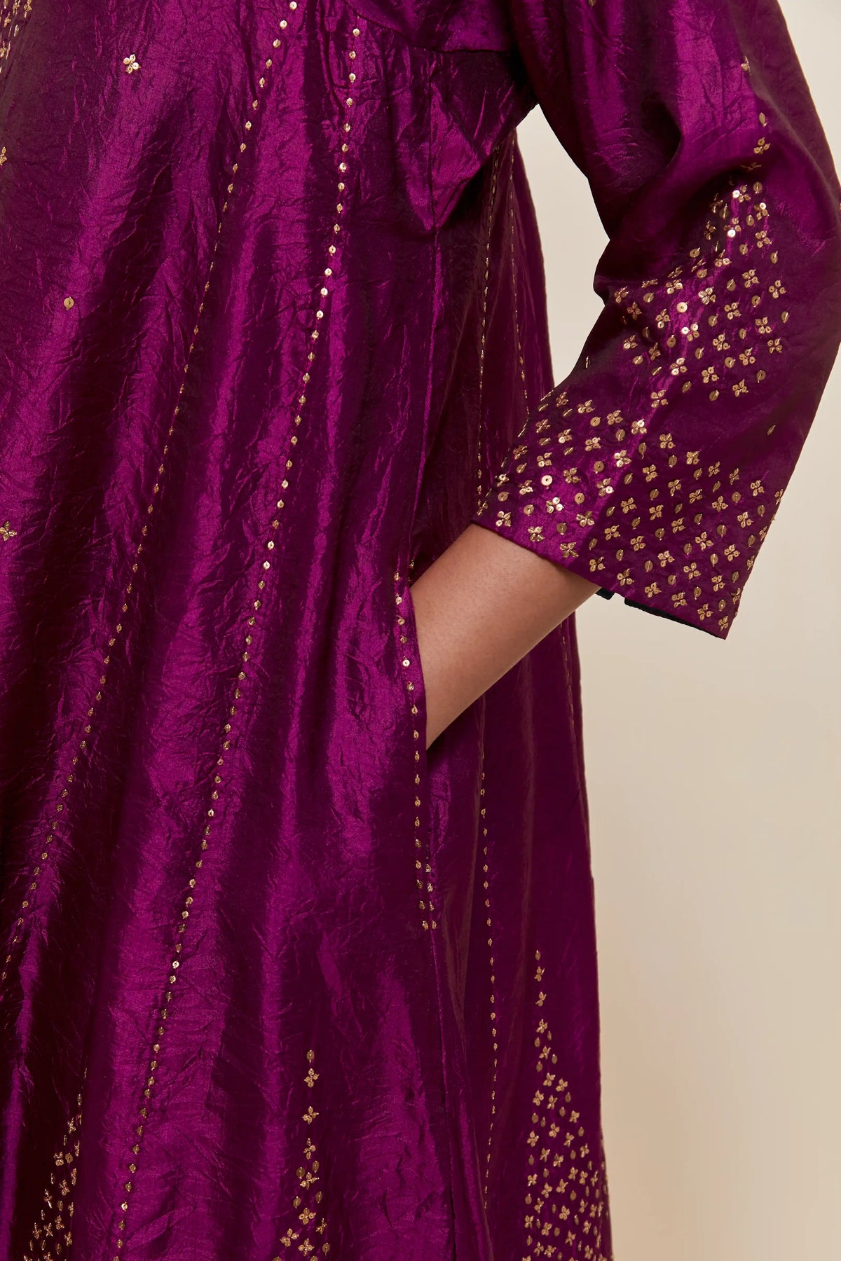 Purple silk short kalidar kurta set, with hand embroidered sequins at neck, hem and sleeve edges, highlighted with scattered gold sequins embellishments all-over.