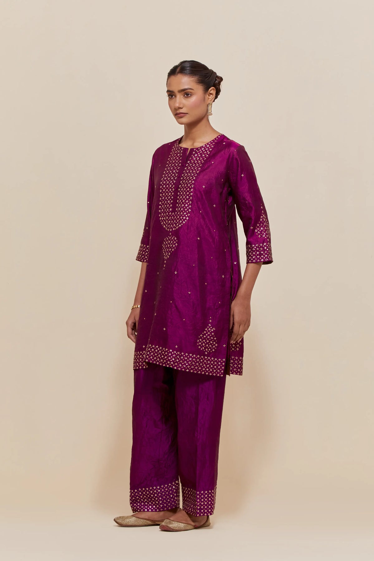 Purple silk straight short kurta set with hand-embroidered sequins at the neck, borders running along the hem and sleeve edges, and scattered gold sequins embellishments all-over.