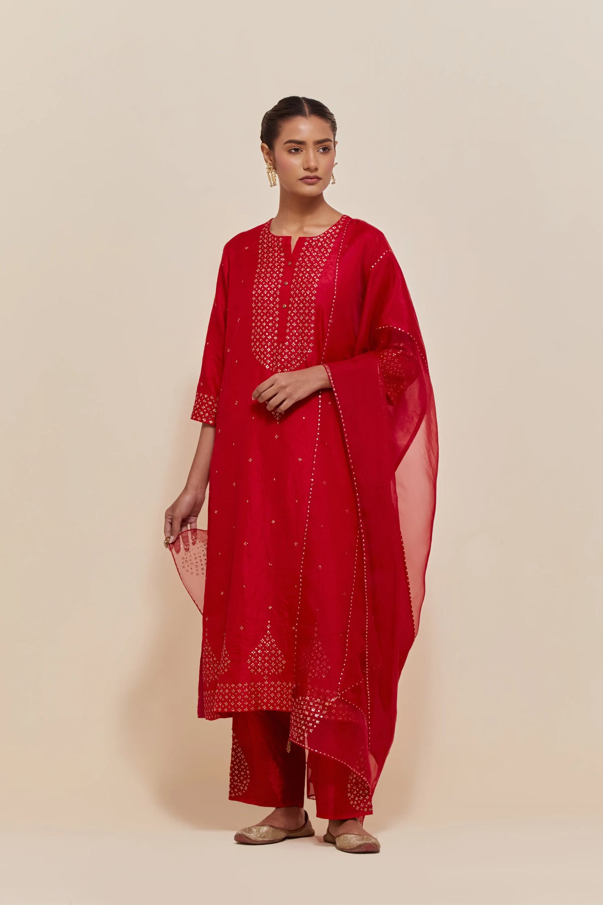 Red silk straight kurta set with hand-embroidered sequins at the neck, borders running along the hem and sleeve edges, and scattered gold sequins embellishments all-over.