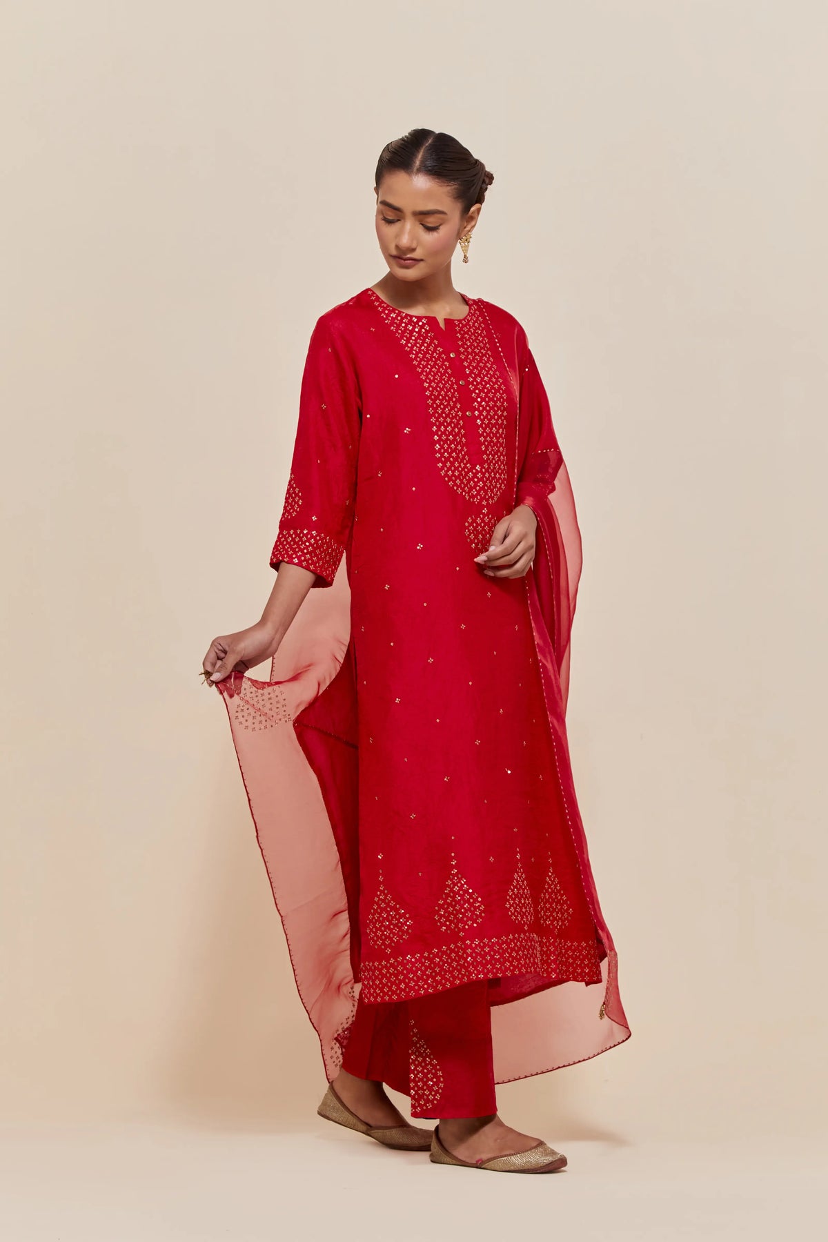 Red silk straight kurta set with hand-embroidered sequins at the neck, borders running along the hem and sleeve edges, and scattered gold sequins embellishments all-over.